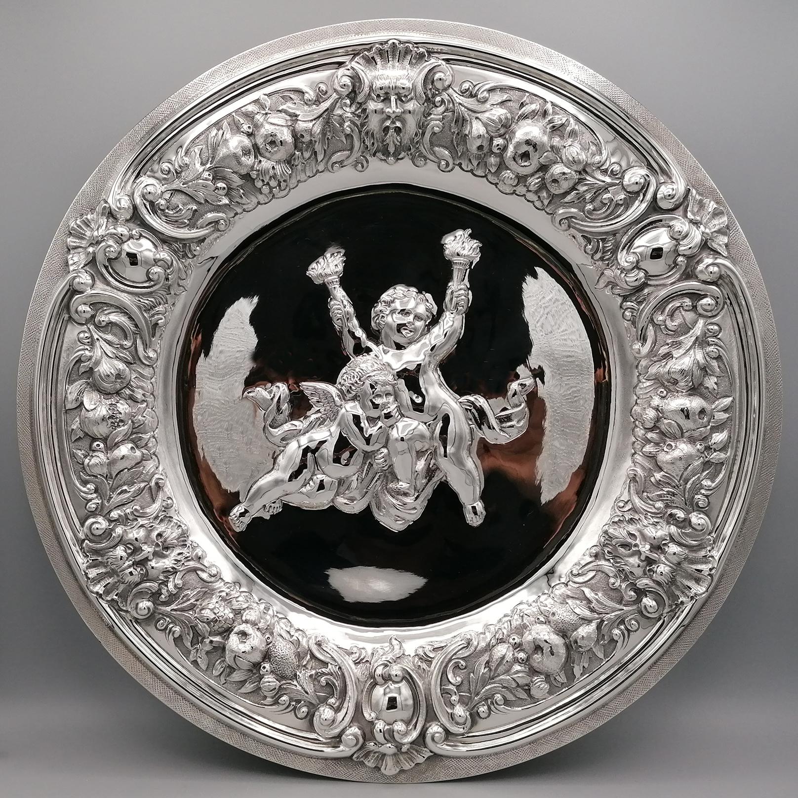Baroque style centerpiece in solid 800 silver, completely handmade and subsequently embossed and chiseled.
The edge of the centerpiece was embossed with fruit motifs and masks, typical of the Baroque period.
The outermost edge has been