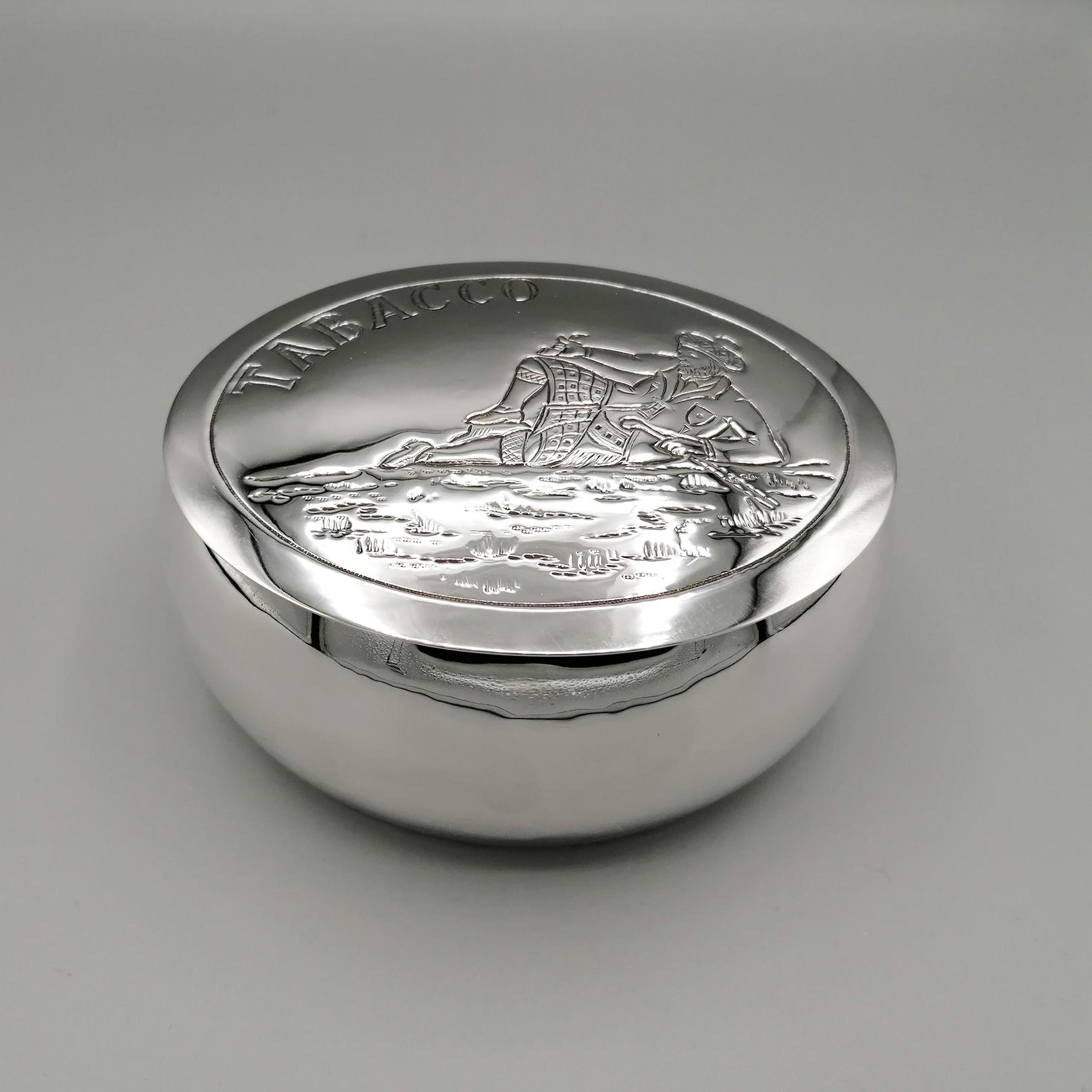 Boîte en argent massif pour le tabac.
La boîte a été entièrement fabriquée à la main, à partir d'une feuille d'argent, puis façonnée et soudée, ce qui lui donne une forme ovale et arrondie.
La partie extérieure du corps de la boîte a été polie