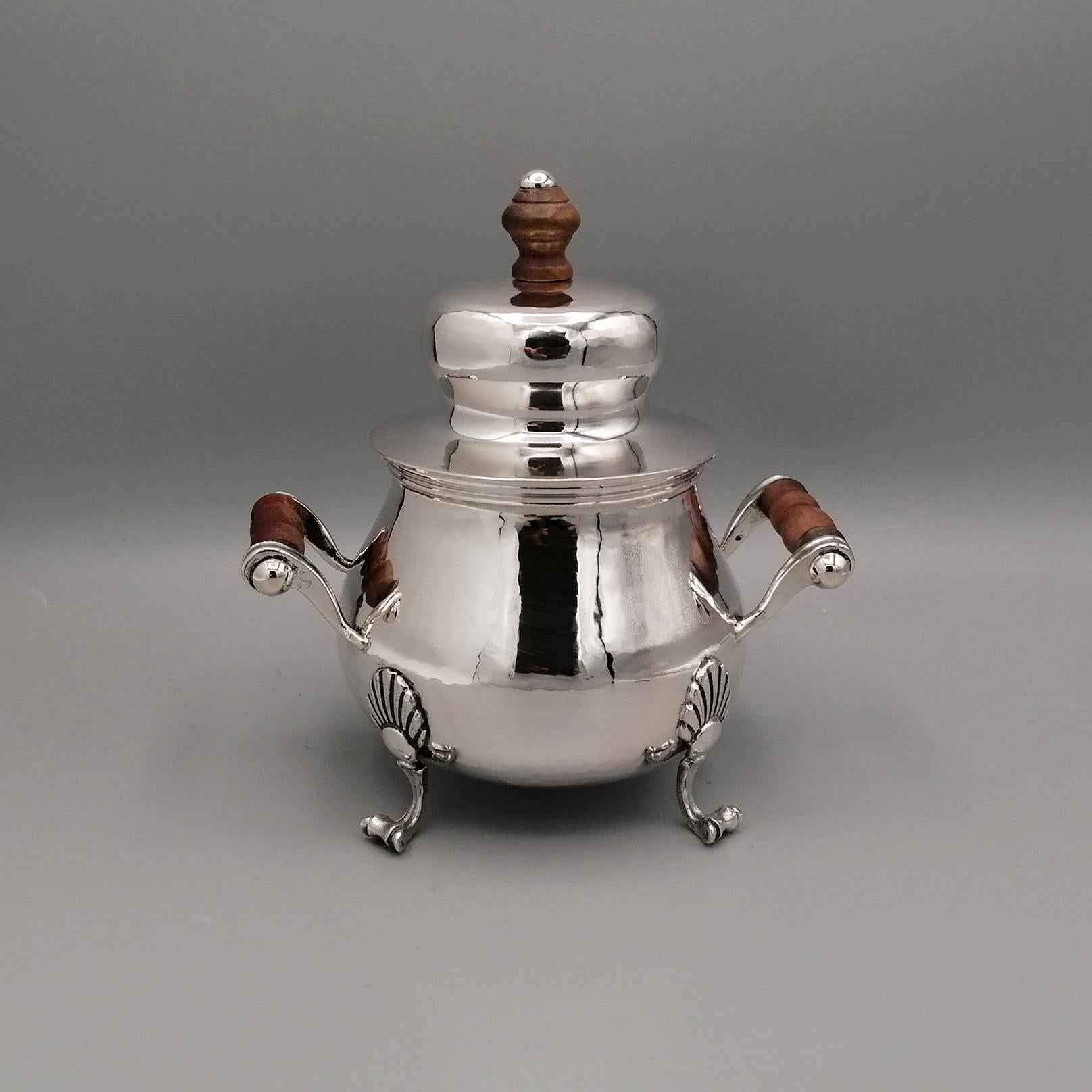 The sugar bowl was made entirely by hand in hammered and shaped 800 silver in the late 18th century style.
The horizontal handles, embellished with a wood finish, were made with the fusion technique.
Even the 4 feet, which allow the stability and