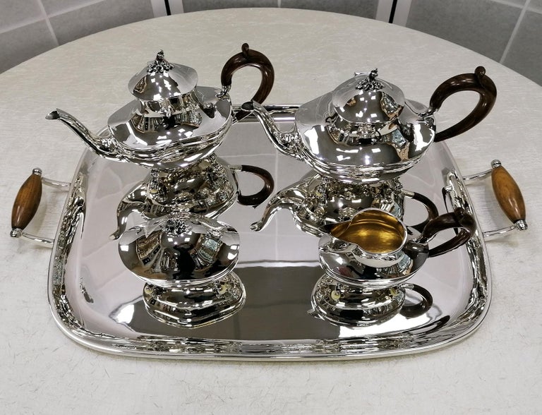 Large oval tea and coffee service in 800 solid silver on feet, completely handcrafted and lightly hammered. The oval shape, particularly difficult to make as it is completely shaped by hand, is completed with a hinge that fixes the lids of the