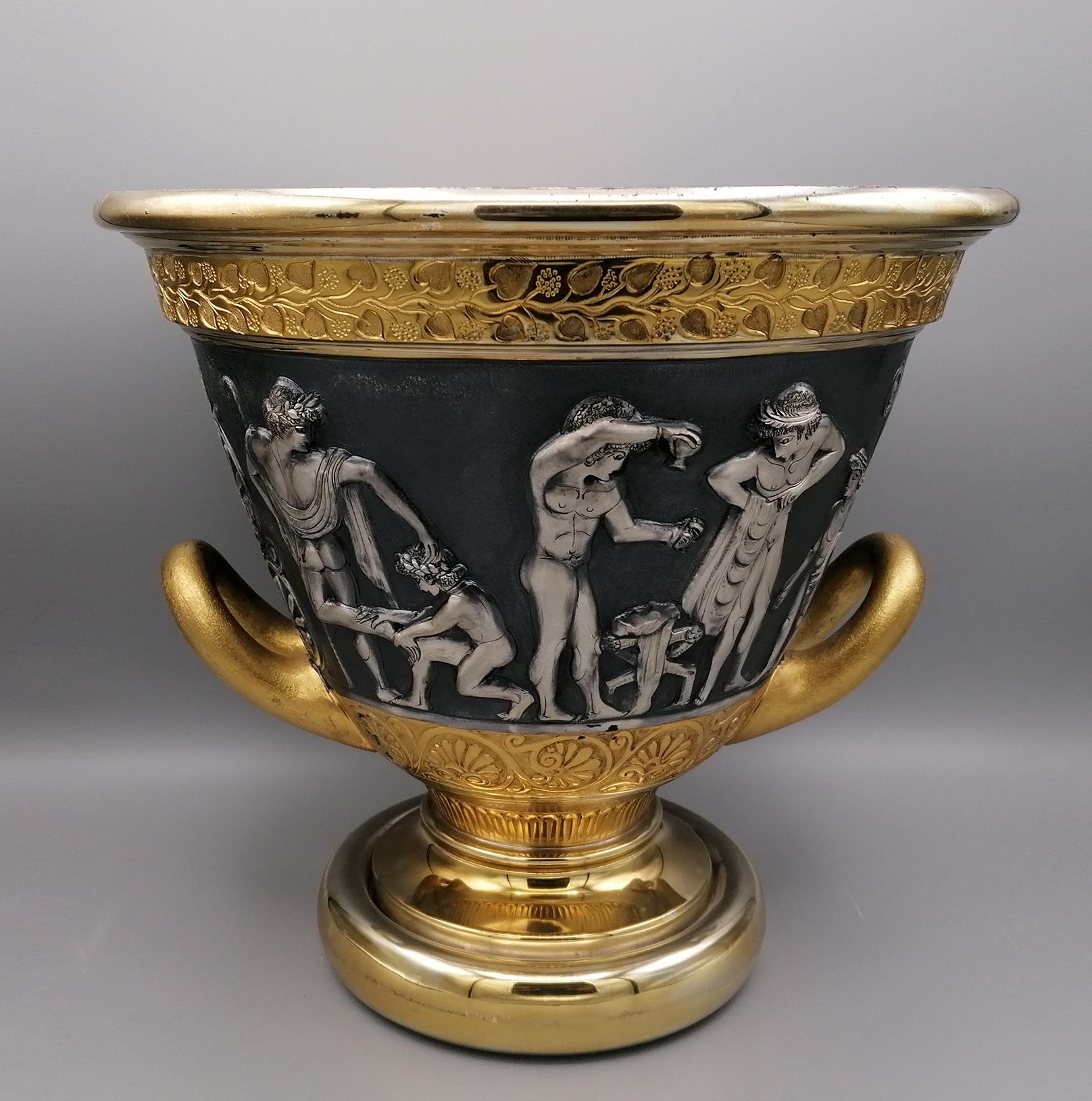 Vaso in stile etrusco con manici in argento, completamente realizzato a mano in Italia in argento massiccio 800.
Il rilievo e lo scalpello riproducono scene di vita etrusca, tipiche del periodo pre-romano.
La base è rotonda e liscia, mentre le scene