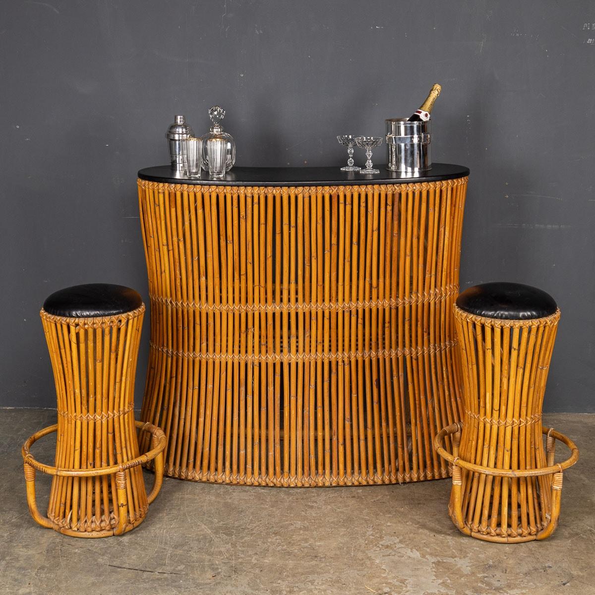 An exquisite vintage cocktail bar and accompanying stools, adorned with bamboo finishes, hail from the stylish era of the mid-1960s. The bar, with its distinctive kidney shape, showcases a sleek black countertop and stool seats, while the interior