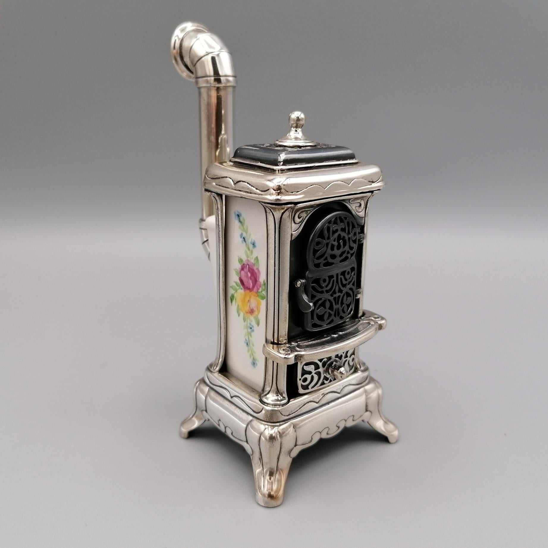 Sterling silver / porcelain wood stove miniature.
The main structure was made of sterling silver while the central body is hand painted porcelain.
Some parts, such as the lid of the stove and the door, have been perforated and burnished to create