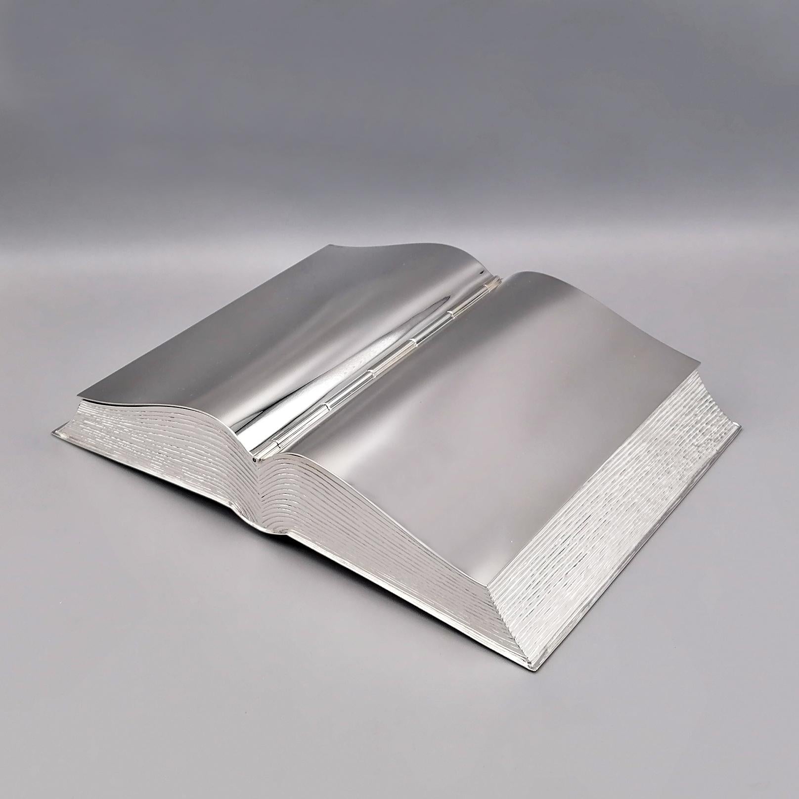 Book-shaped sterling silver solid box.
The box has been completely handmade, faithfully reproducing the shape of the book.
The two hinged and shaped pages are the lid of the box and are completely smooth to be easily personalized with engraving.
The