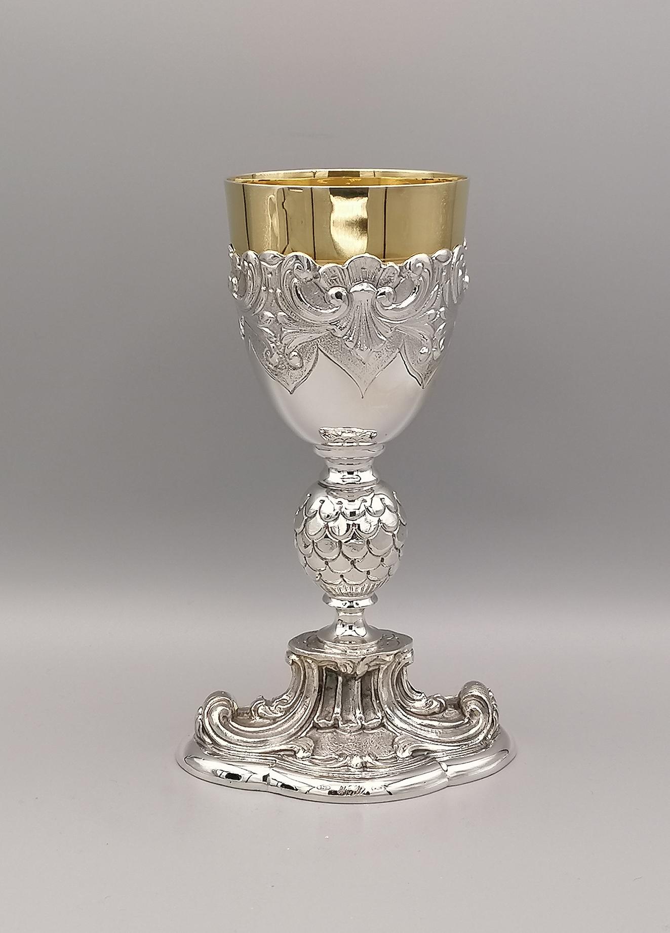 Ecclesiastical chalice in sterling silver in Baroque style. The shape is unusual, characterized by the oval cast base with volutes typical of the Baroque style.
The stem is also worked in fusion, while the golden cup is placed on another cup