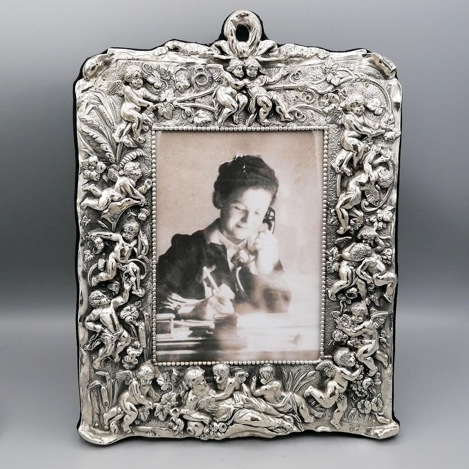 Sterling silver frame depicting scenes with cherubs and angels.
The workmanship is in lost wax and finished with chisel. 
Then subsequently burnished and antiqued
The measure of the photograph is 13x18 cm
Italian silverware, already with a