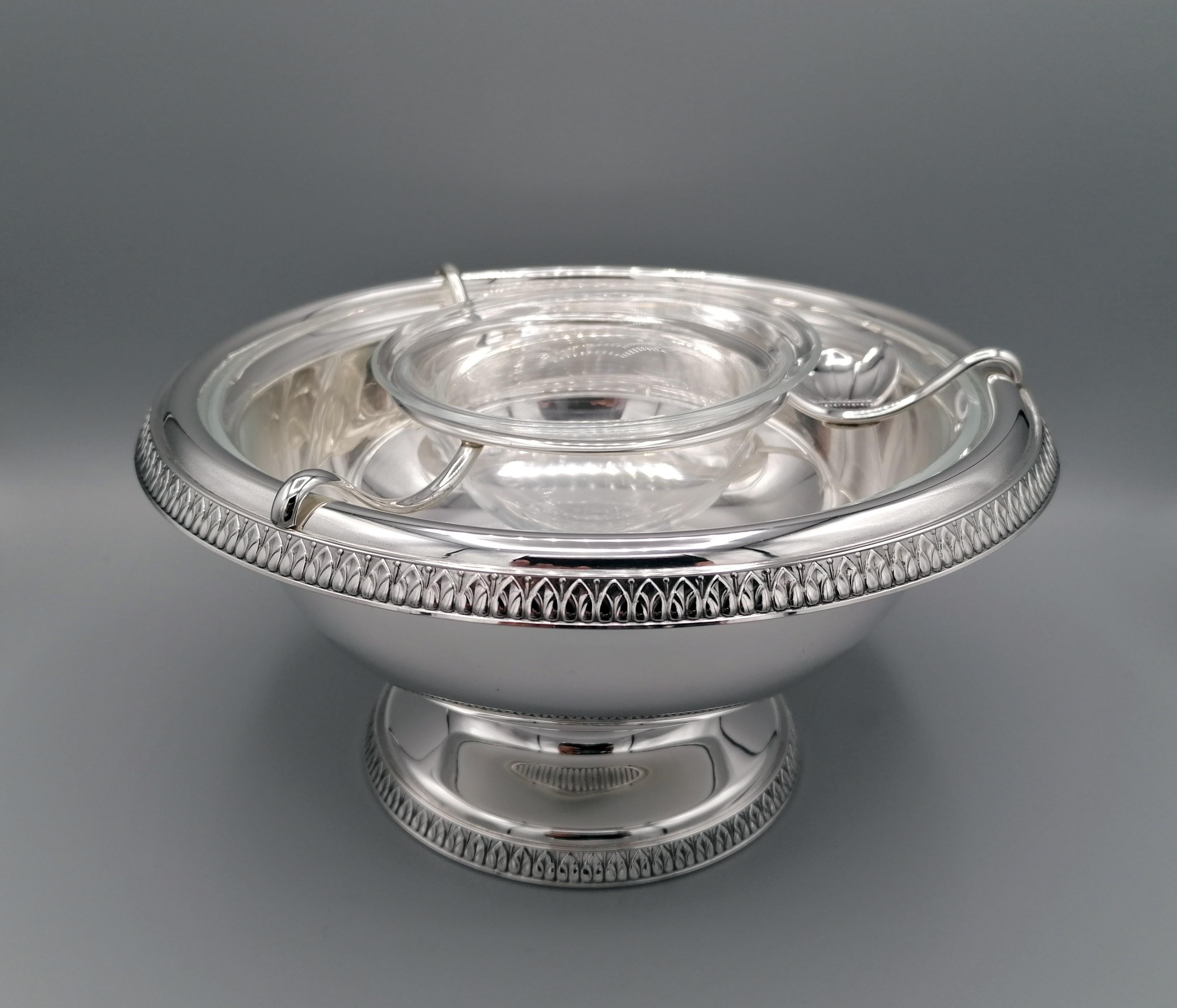 Important bowl for caviar by Gianmaria Buccellati. The body was made in two parts, cup and base. The welded edge with small leaves characterizes the Classic Empire style.
A wire circle, also in silver, supports a crystal cup for caviar, while a