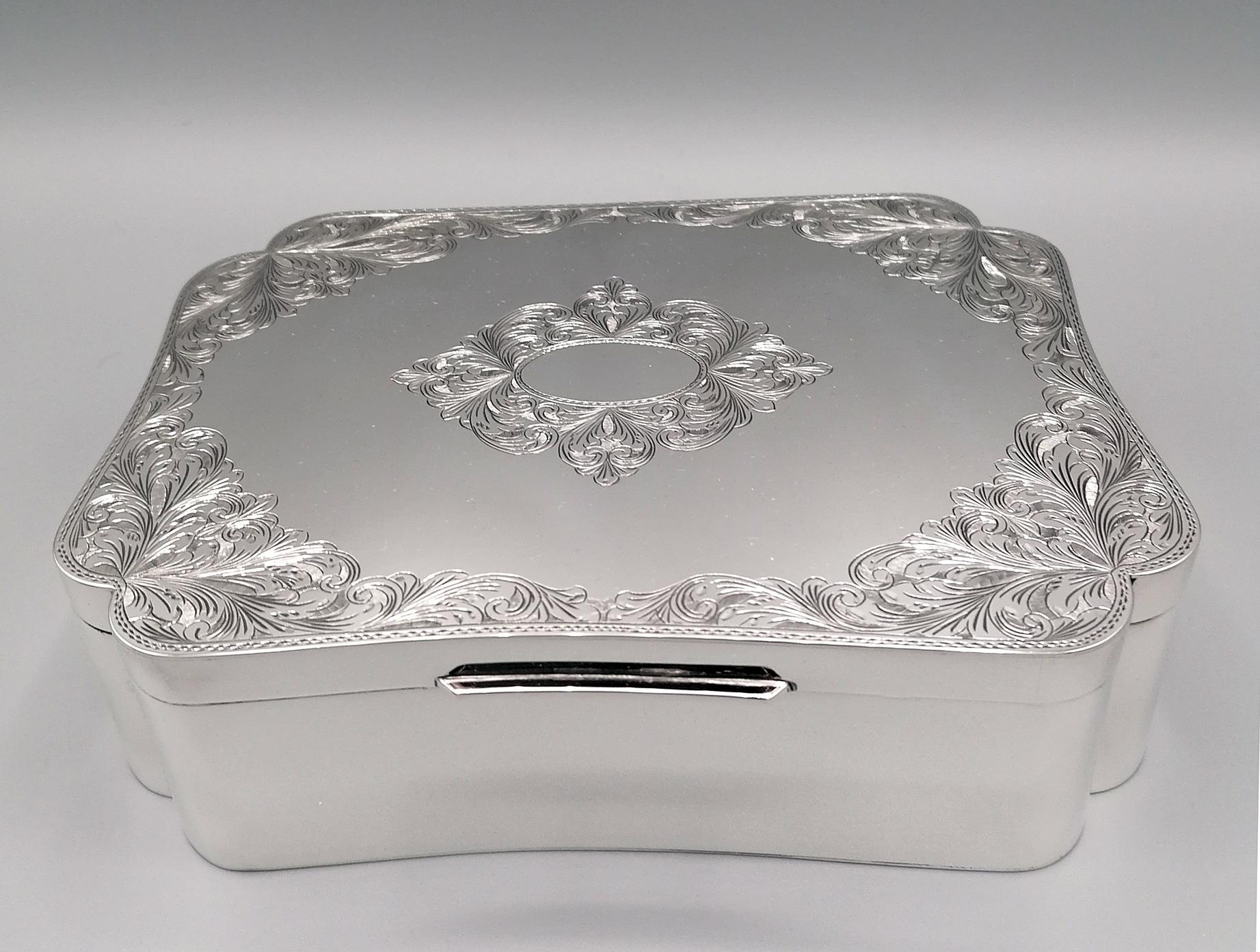 Joyero de plata de ley 925. El cuerpo de la caja tiene forma rectangular, lo que hace que su línea sea ligera y armoniosa. La tapa abatible está grabada a mano con volutas y lirios florentinos que embellecen su forma. En el centro de la caja, entre
