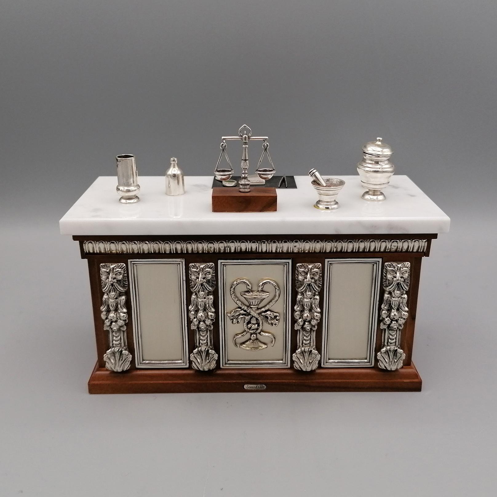 Pharmacist's workbench.
This miniature has been masterfully handcrafted by reproducing in detail an antique workbench of a 200 year old pharmacy.
The structure is in wood while the table has a white Carrara marble top.
The details, such as the doors