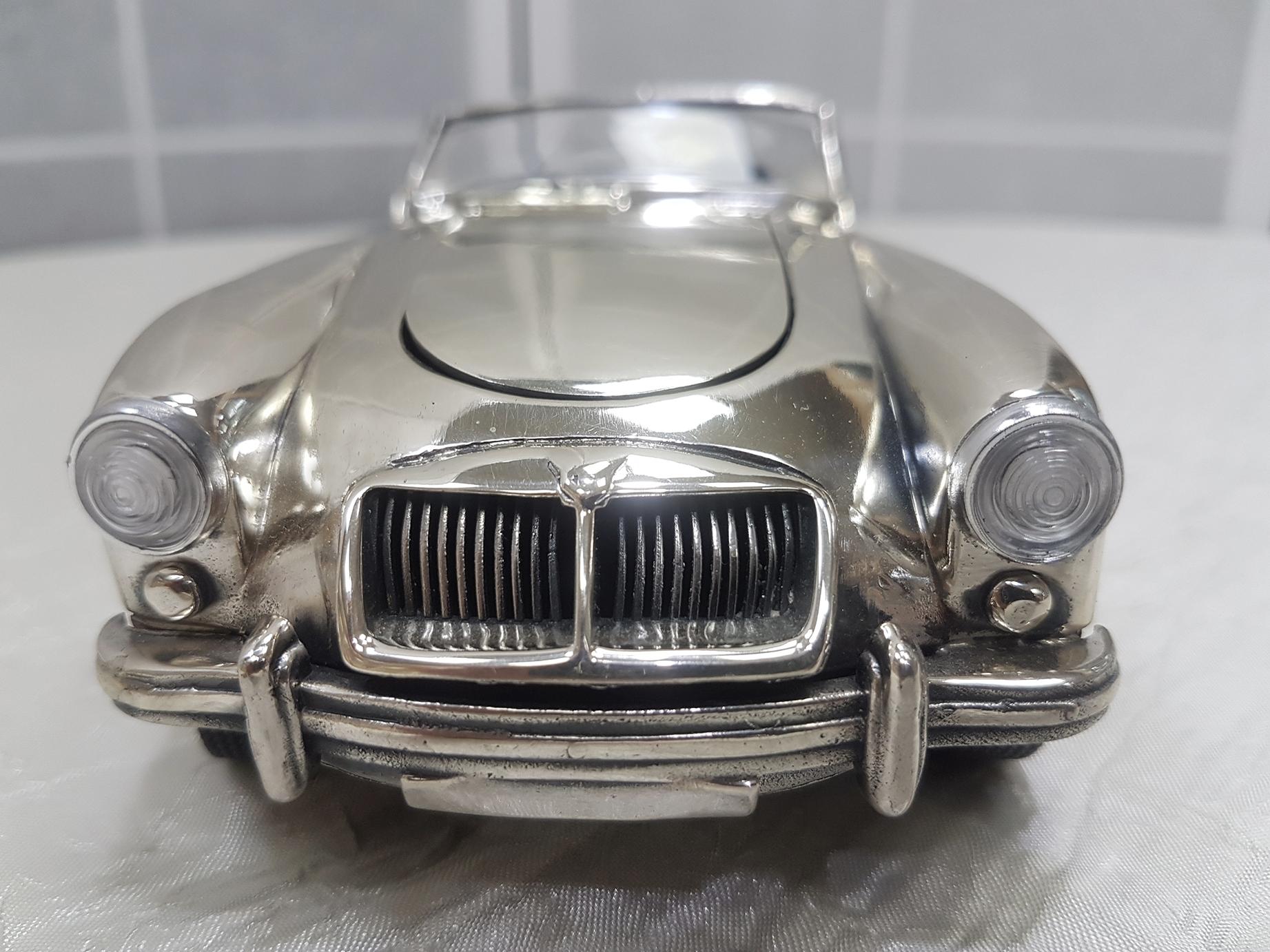 Reproduction in sterling silver MGA Twin Cam in sterling silver. The steering wheel is steering and the doors and the hood of the car can be opened. 
The tires are rubber reproducing the originals mounted on the car
The weight is 1320 grams of