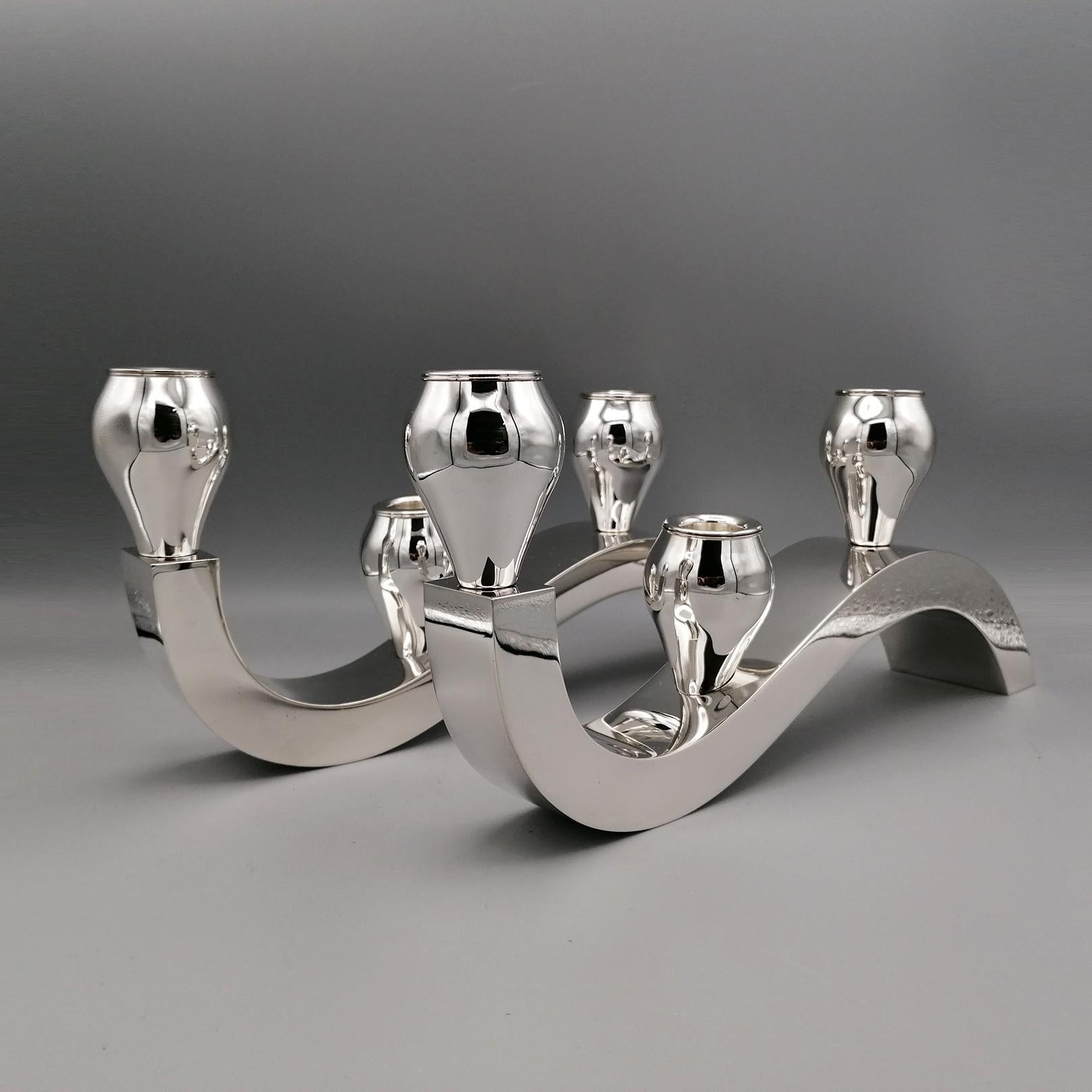 Pair of sterling silver candelabra with three lights.
The structure has been realized by a smooth sheet of silver.
The wave movement is realized with manufacturing by handmade.
On the top three rounds candle-holders are placed to complete the