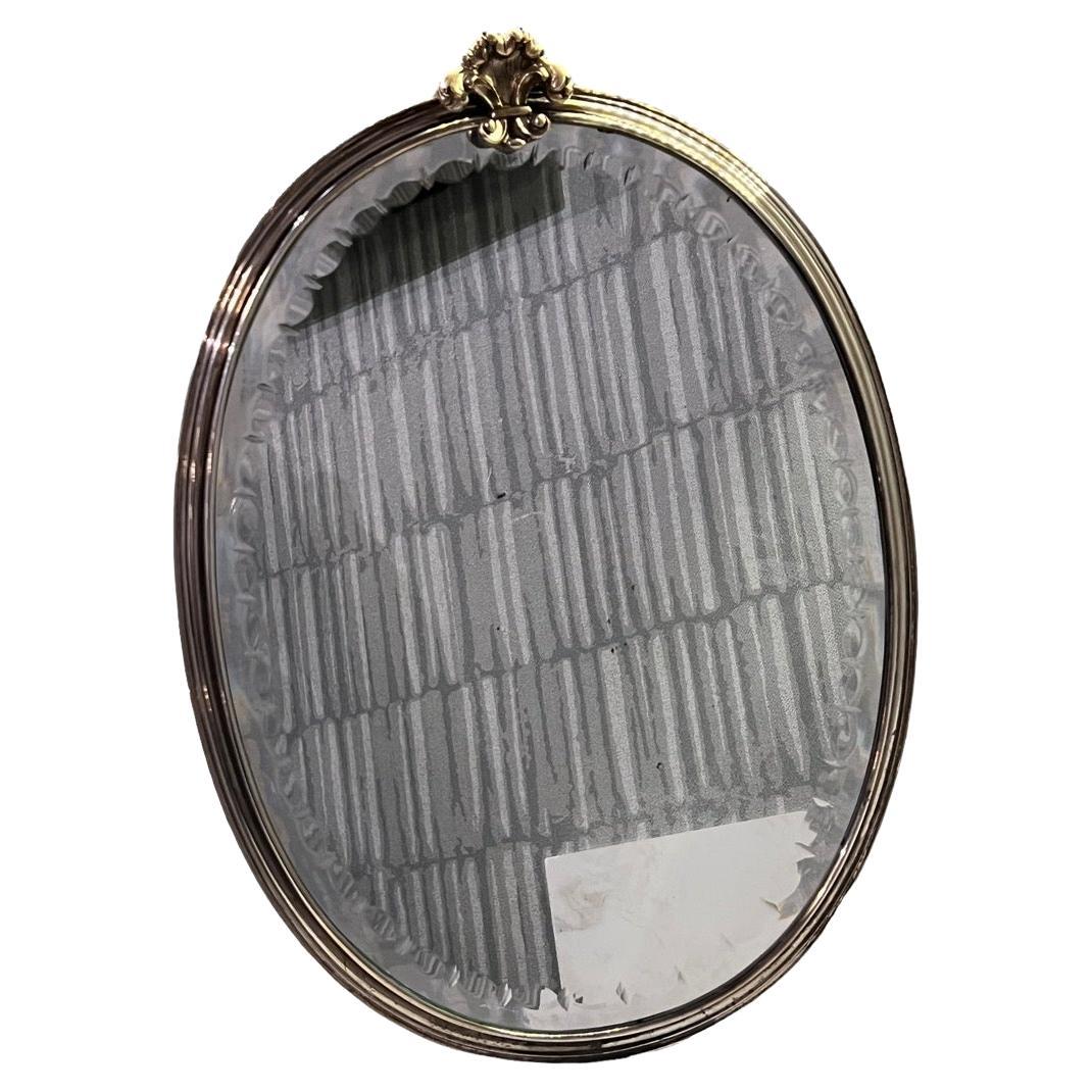 20th century Italian sterling silver oval mirror by Mario Buccellati, which is engraved on back. It is topped with a fleur-de-lys, faceted glass, leather back with easel Stand and a hanging hook

Easel Stand Open measures 7.5in (Wide open).