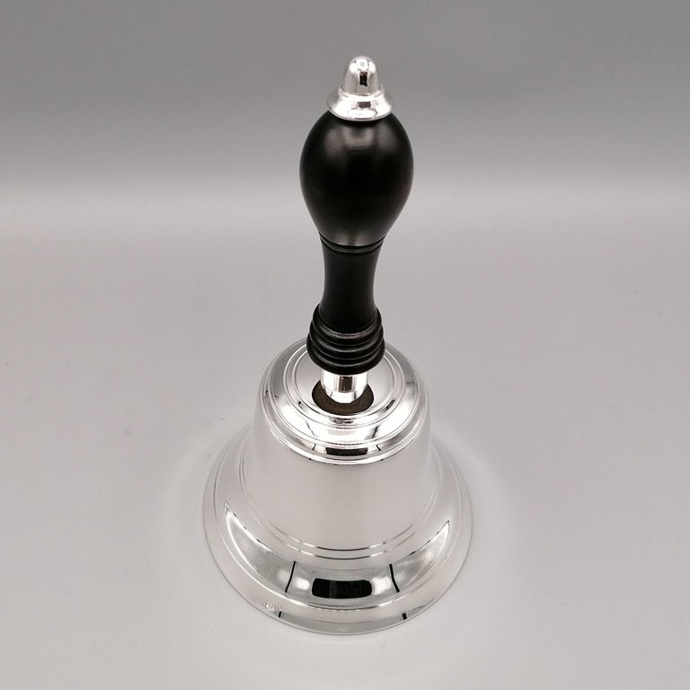 Elegant table bell in solid 925 sterling silver. 
The bell is smooth and features some circular lines that make the object balanced and increase the sound of the bell.
The wooden handle is shaped to improve the grip and is finished in the upper