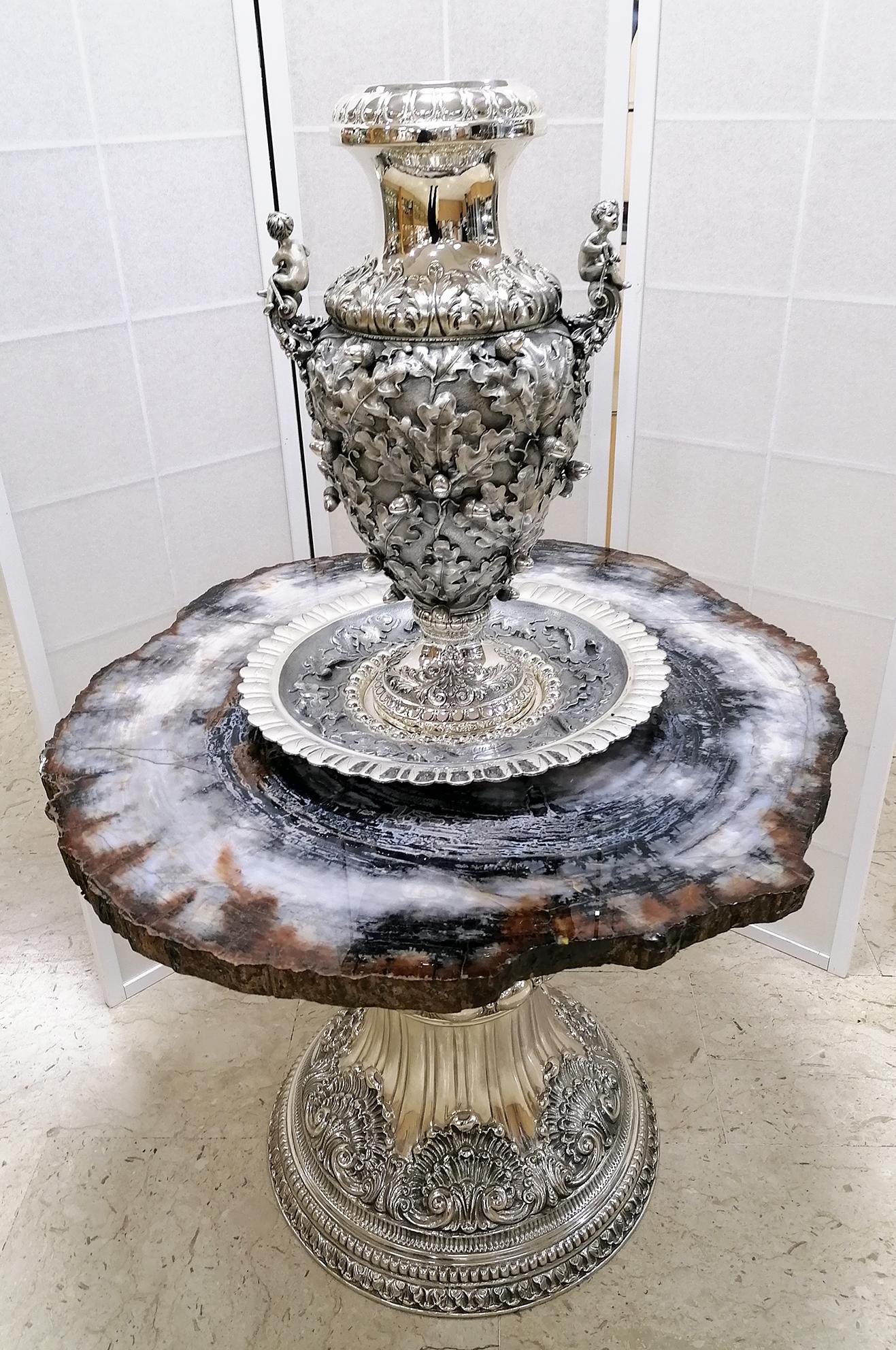 Exceptionnelle table avec vase et assiette en argent massif composée de.. :

Table en argent italienne du 20e siècle. Le dessus est en brun Slab Fossil American Sequoia
La base de la table est en argent massif 925°°/°°° en style baroque italien avec