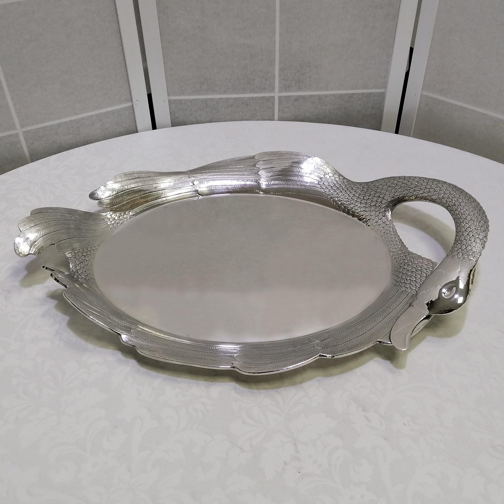 Unusual sterling silver tray in the shape of a swan.
Oval in shape, the central part is smooth and polished with pumice stone, while the edge has been embossed, chiseled and engraved.
The swan's head, folded back on itself, forms an opening where