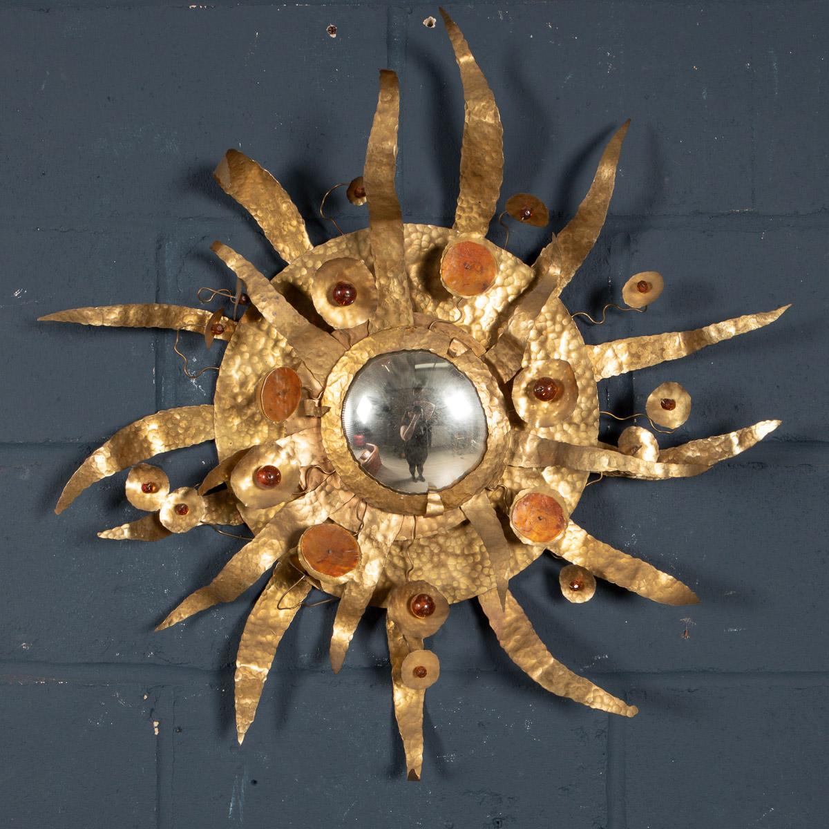 A wonderful and rare sunburst mirror made by Missoni, Italy circa 1980. A convex mirror surrounded by hammered brass and glass cabochons, this is an extremely eccentric item of furniture sure to capture attention and uplift any