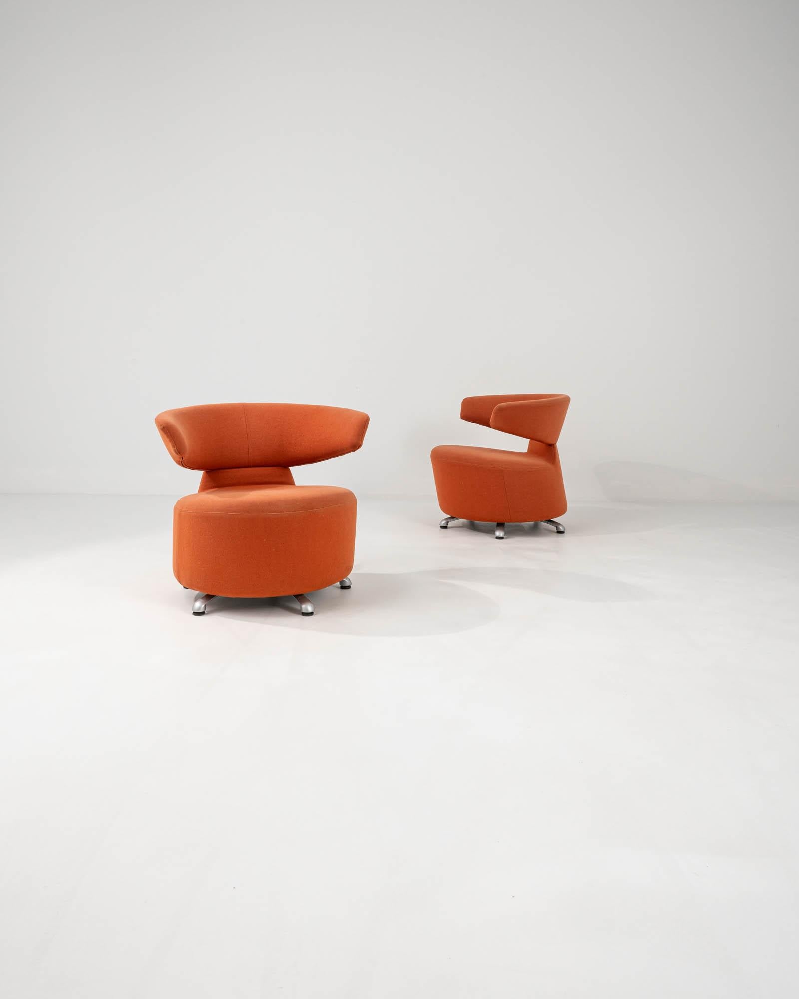 These upholstered lounge chairs were made in Italy in the 20th Century. The swiveling motion fits to the sleek style and sense of movement which define these colorful chairs. Upholstered in a sunset orange hue, the vibrant color enhances the