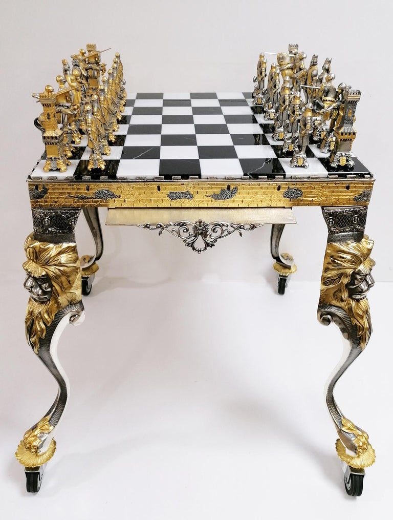 Chess table and chess game in bronze and brass made with the ancient casting technique.
After the casting, the finishing was chiseled and subsequently silvered and finished with 24-karat gilding.
The chess top has two drawers formed by two removable
