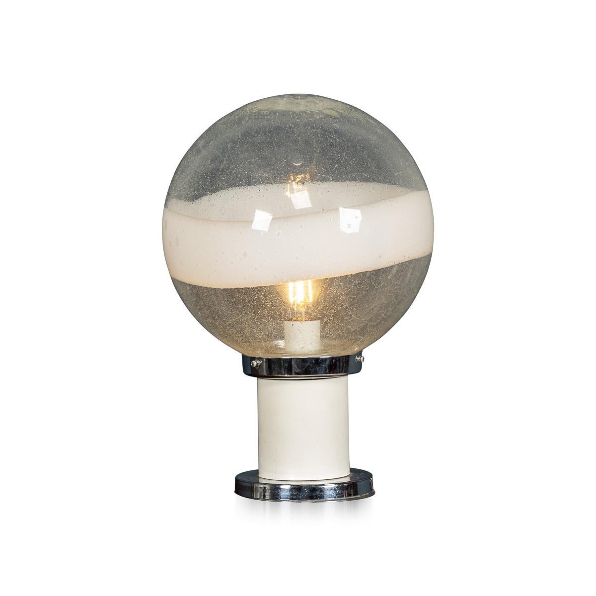 A refined chrome and glass table lamp, originating from Italy in the midst of the 20th century. This exquisite piece of lighting artistry boasts a chrome stand that elegantly supports a meticulously handcrafted glass ball, a testament to the
