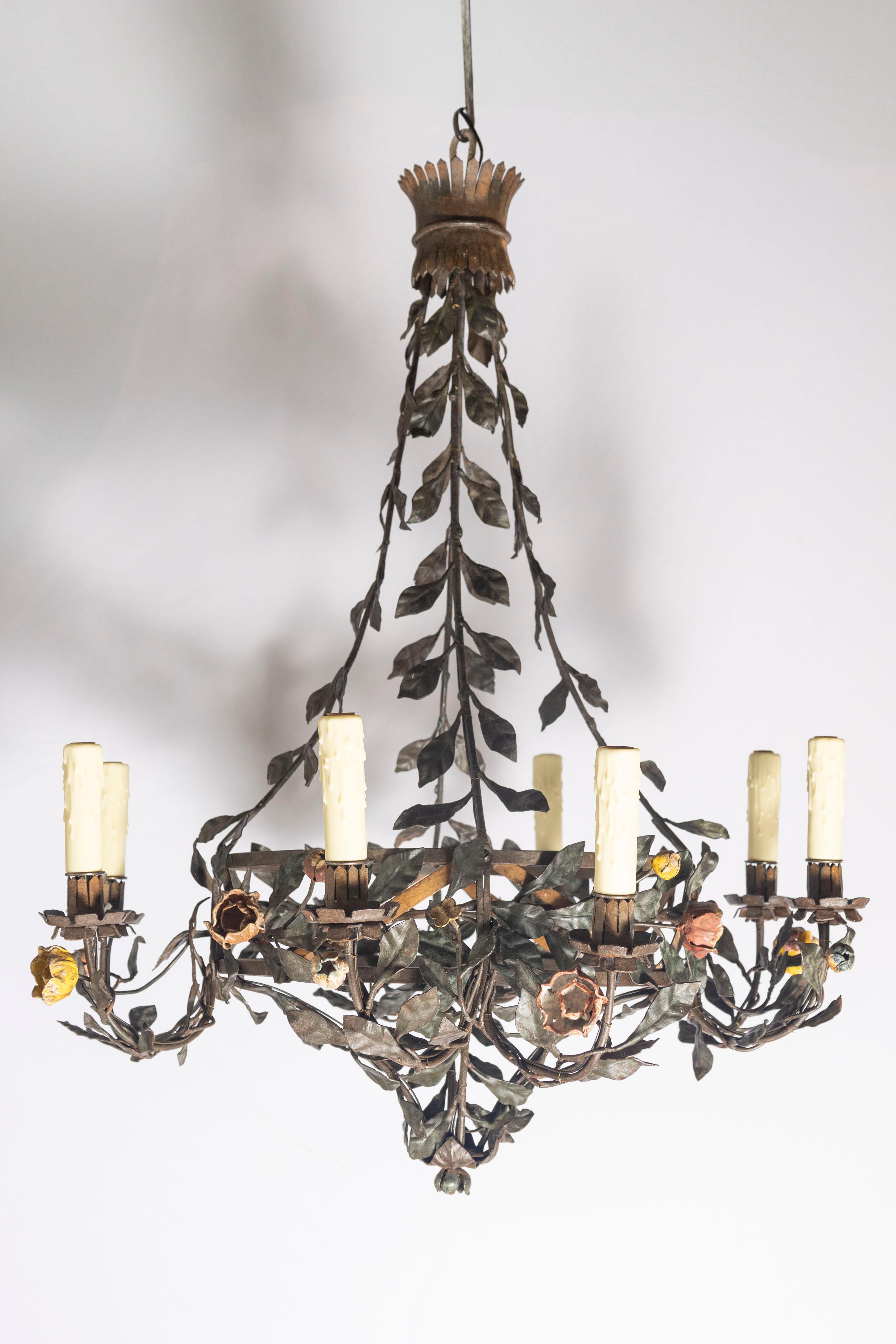 Evocative of romantic Mediterranean gardens, this mid-20th-century Italian tole chandelier is a poetic celebration of nature and craftsmanship. Hand-forged from iron and delicately painted, the piece is richly adorned with winding vines, lifelike