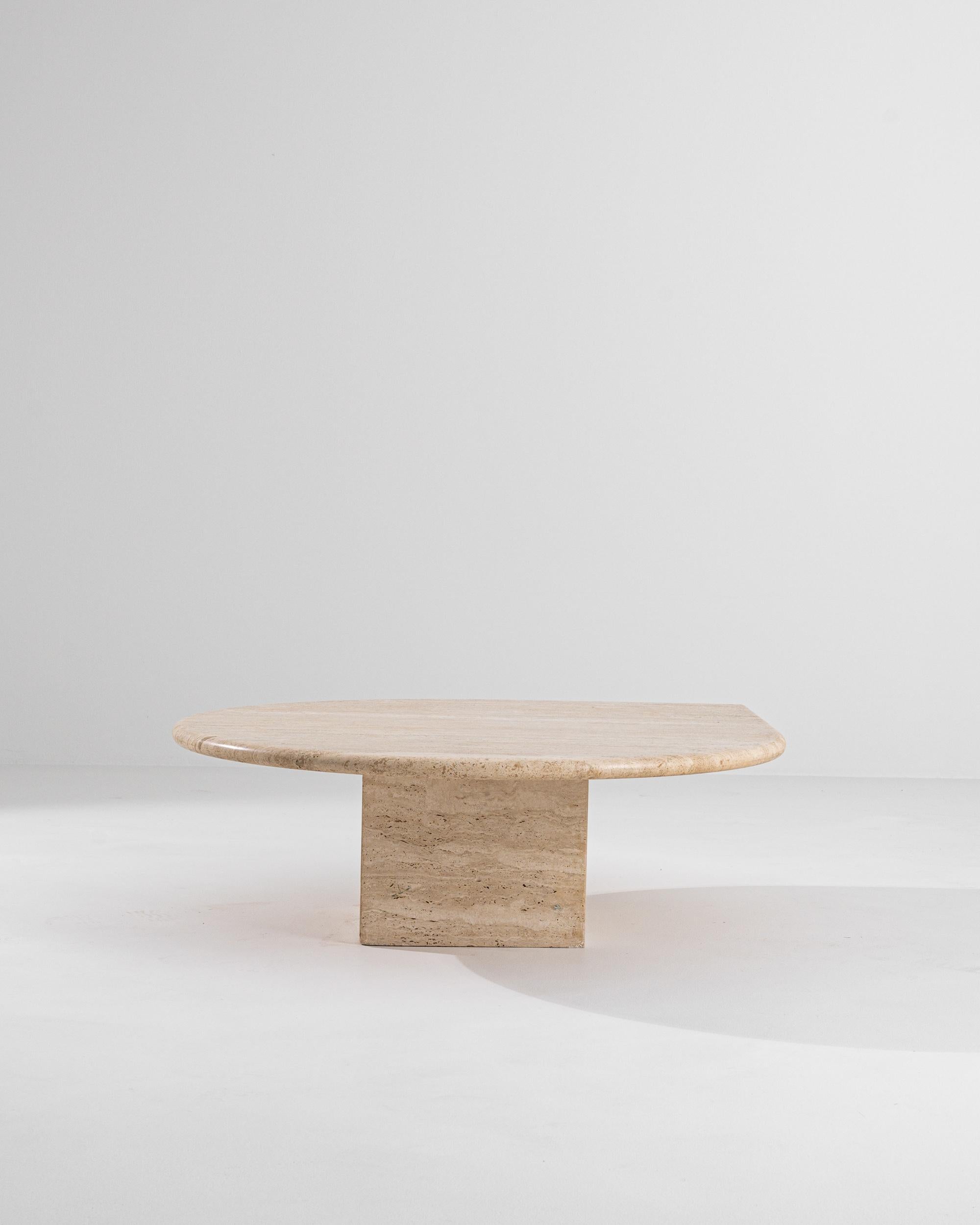 The formal simplicity and rich materiality of this travertine marble coffee table create an impression of minimalist elegance. Made in Italy in the 1970s, a rounded top comes to a single point, resting gently on a low stone pedestal. The warm