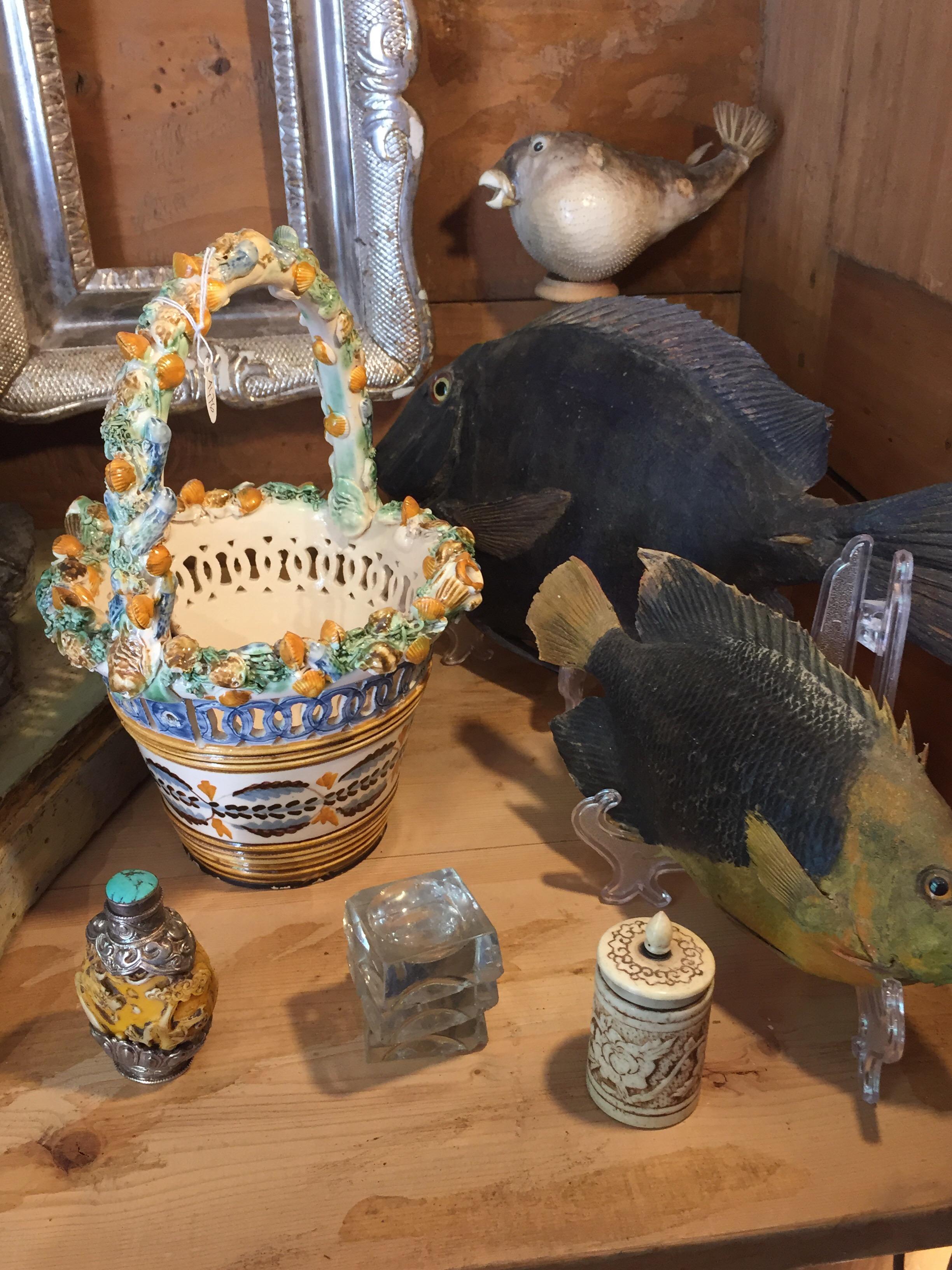 Cestino in ceramica decorata e traforata realizzato con un vaso circolare con decorazioni geometriche policrome sul corpo e una decorazione a rilievo sul bordo realizzata a mano da molteplici conchiglie e piccoli pesci, oltre che sul manico.
Due