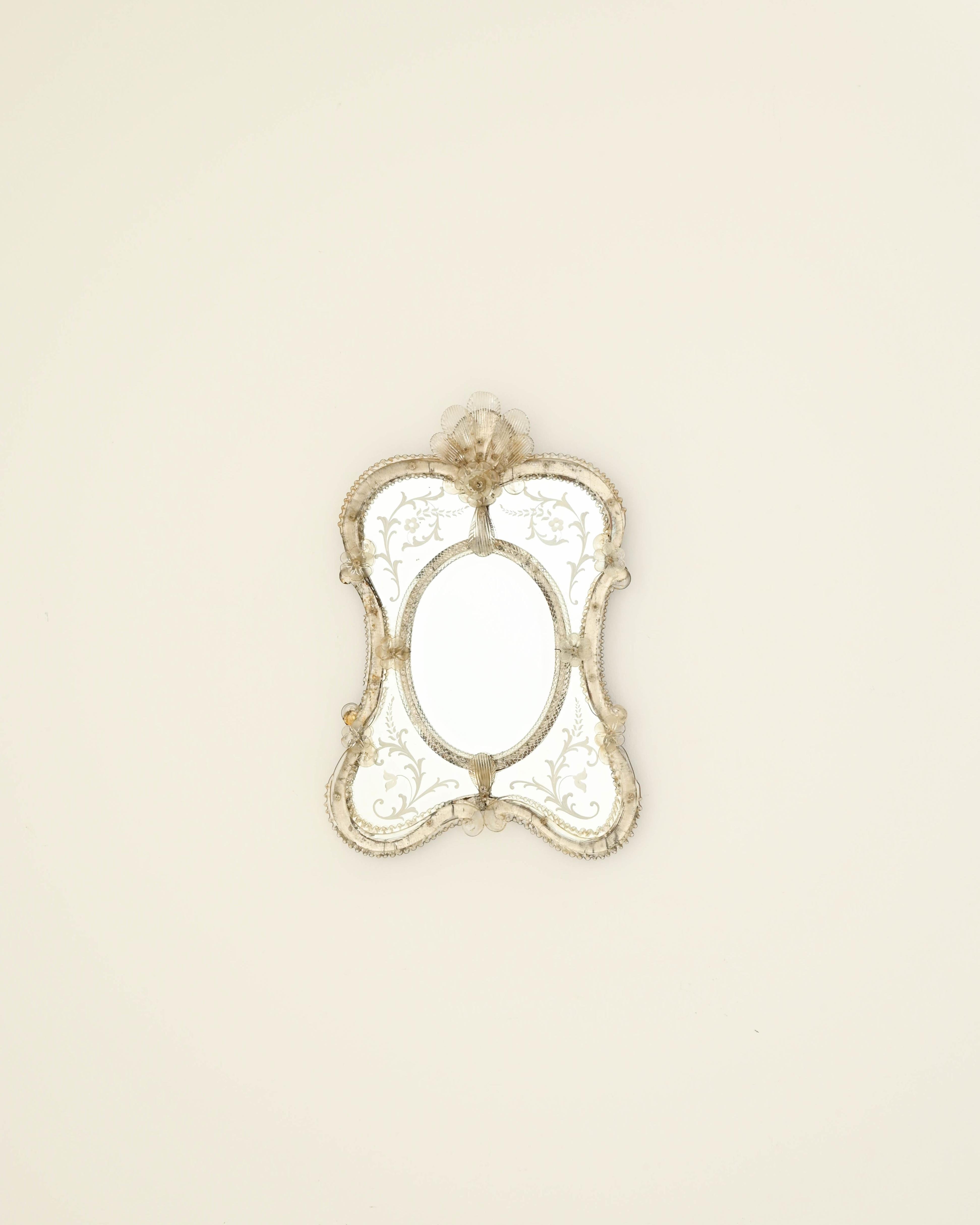 Crafted in Italy during the 20th century, this exceptional wall mirror showcases an exquisite, curvaceous shape with smoothly rounded corners and edges adorned with hand-crafted glass frills and scrolls, adding multidimensionality to its appeal. The