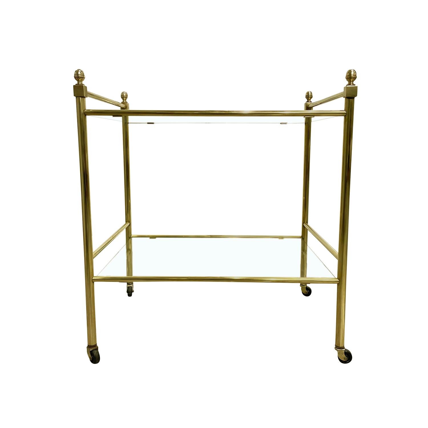 A vintage Mid-Century Modern Italian side, sofa table made of hand crafted brass, in good condition. The serving, tea table is composed with two tier glass tops, supported by four round legs, standing on small wheels. Wear consistent with age and