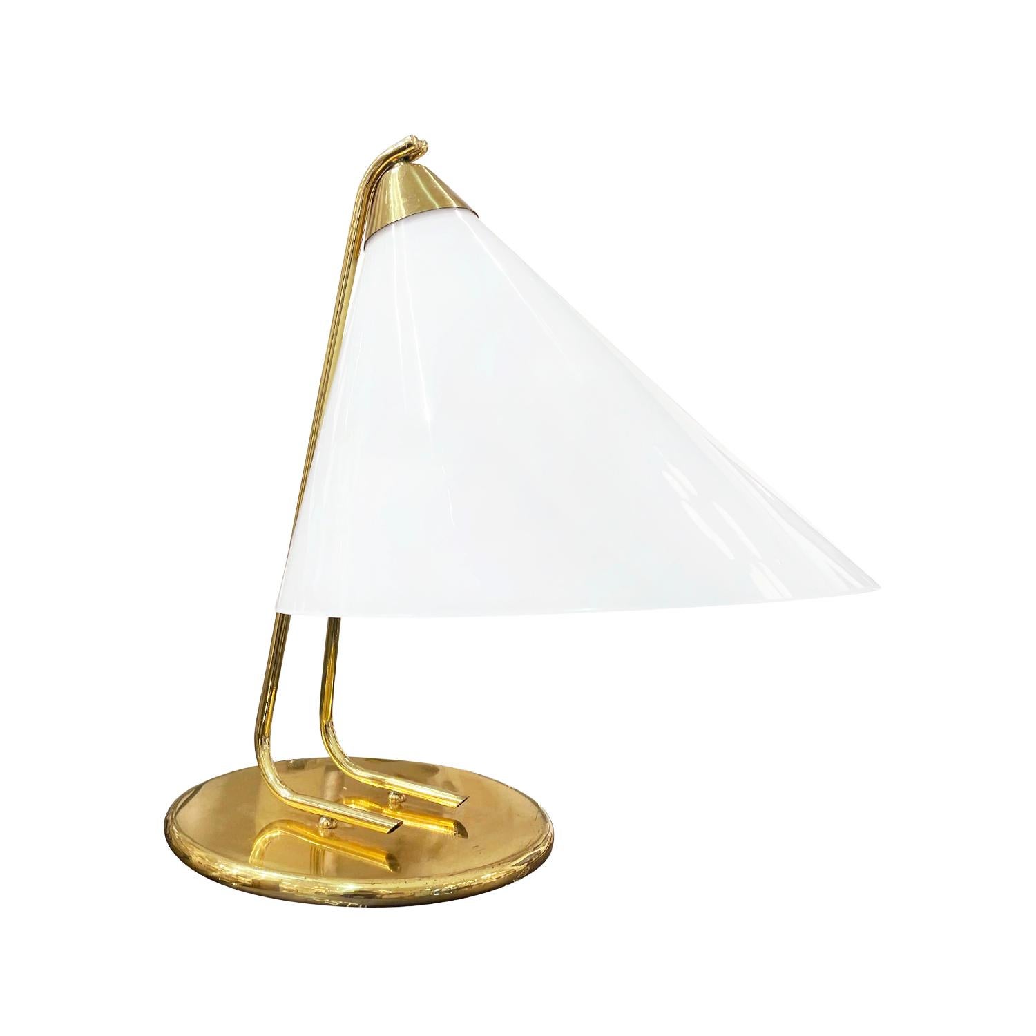 A vintage Mid-Century modern Italian table lamp made of hand crafted polished brass, designed and produced by Stilnovo in good condition. The sculptural desk light is particularized with a large white shade which is made of hand blown frosted