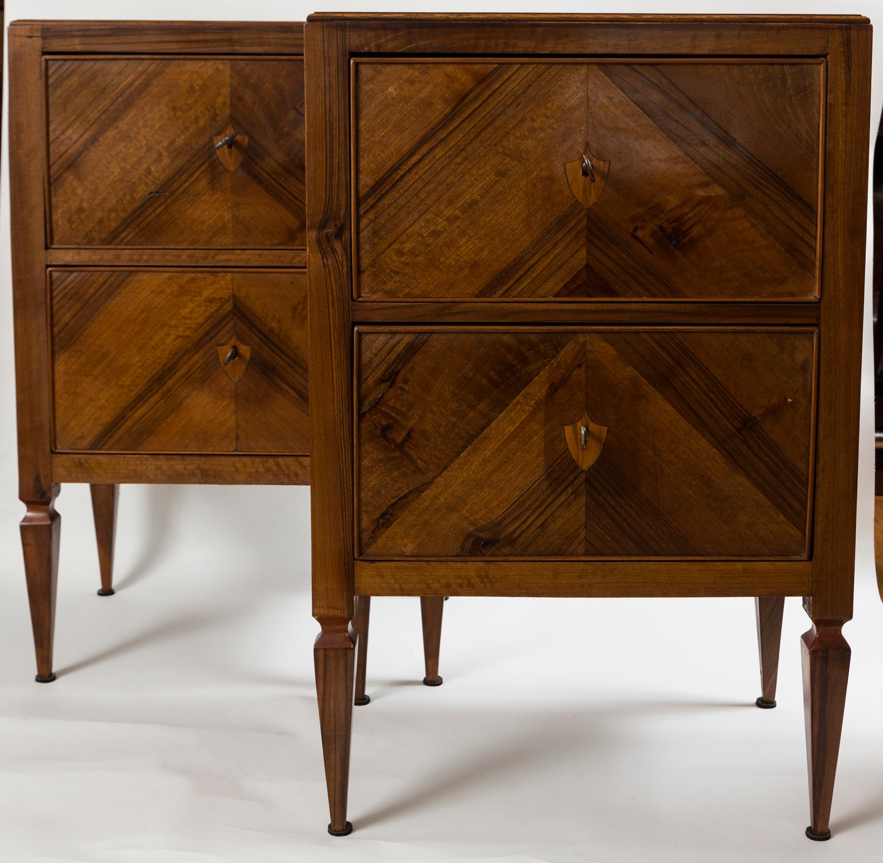  A charming pair of narrow chests comprised of 2 drawers finishing on high tapered and squared legs and embellished with  inlaid shield shaped escutcheon key holes.  Made from solid walnut with secondary wood in pine. A key provided for each