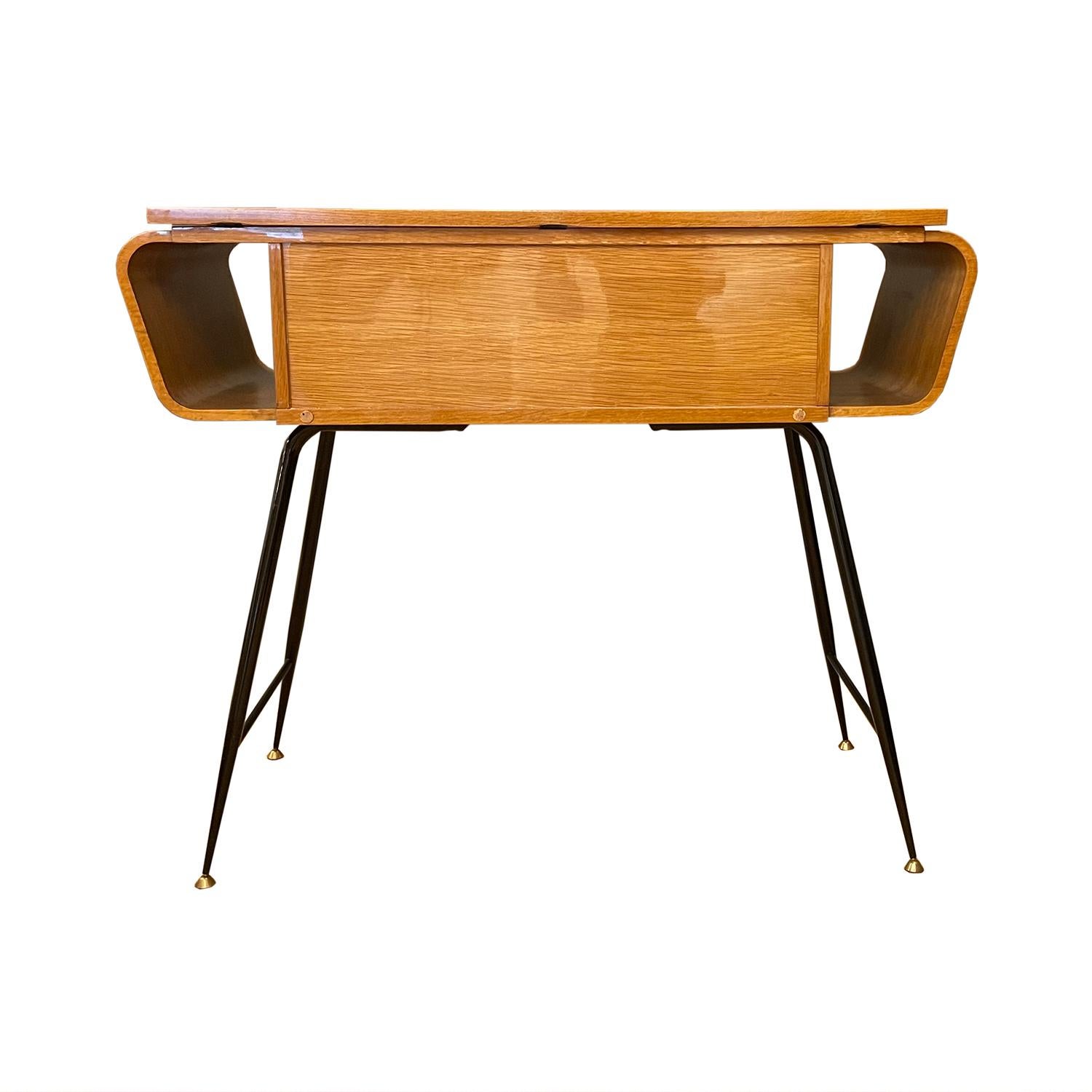 A vintage Mid-Century Modern Italian console table with two small, push out drawers, made of hand carved lacquered veneered Walnut, in good condition. The side, free standing table is standing on four curved metal, brass spider legs, designed by Ico
