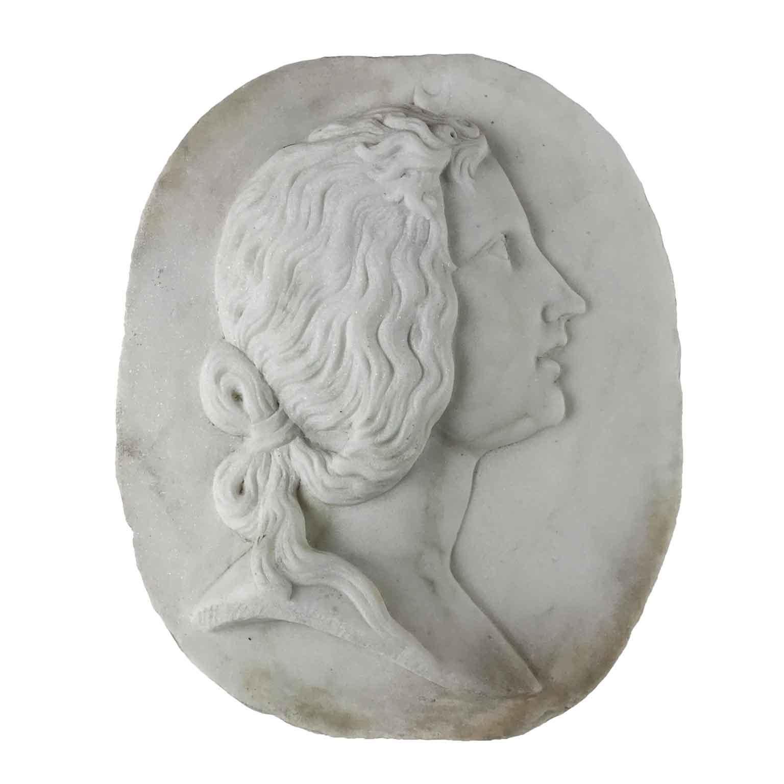 An oval Italian Carrara marble relief plaque, an early 20th century hand-carved marble profile lady portrait, depicting a female head, possible Artemis or Diana Goddes, a woman with long wavy hair tied with a ribbon behind her neck, portrayed in