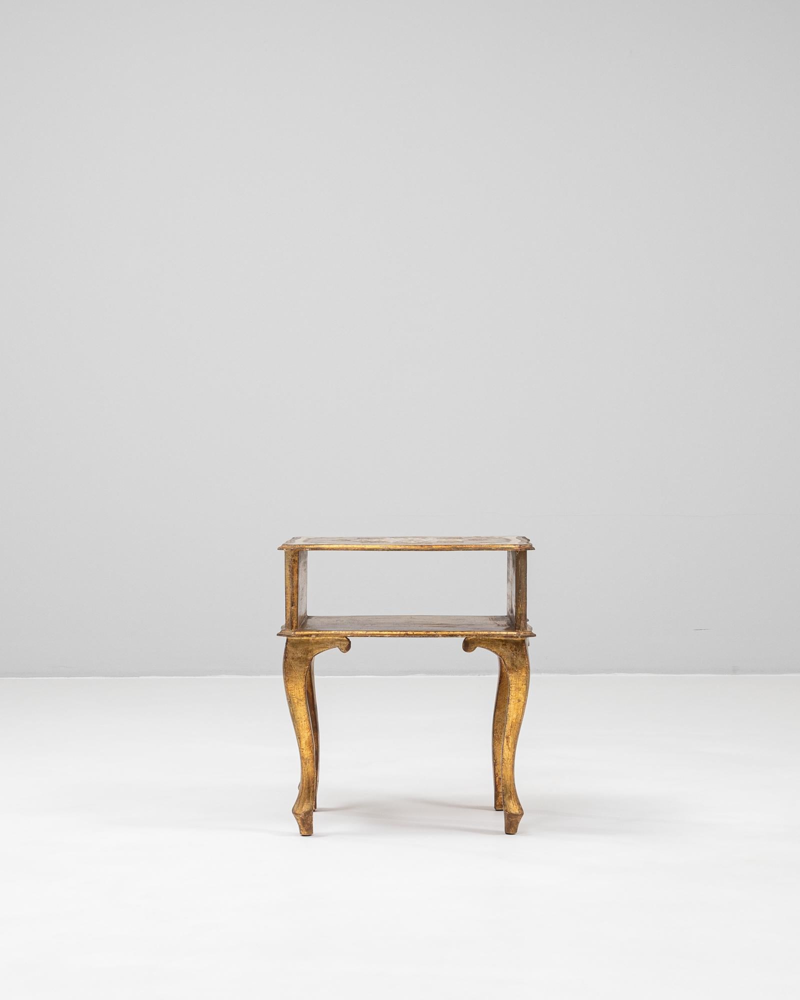 This 20th century Italian bedside table captures the charm of Venetian craftsmanship with its hand-painted gilt finish and graceful cabriole legs. The wooden structure features a beautifully aged patina, revealing subtle layers of gold and muted