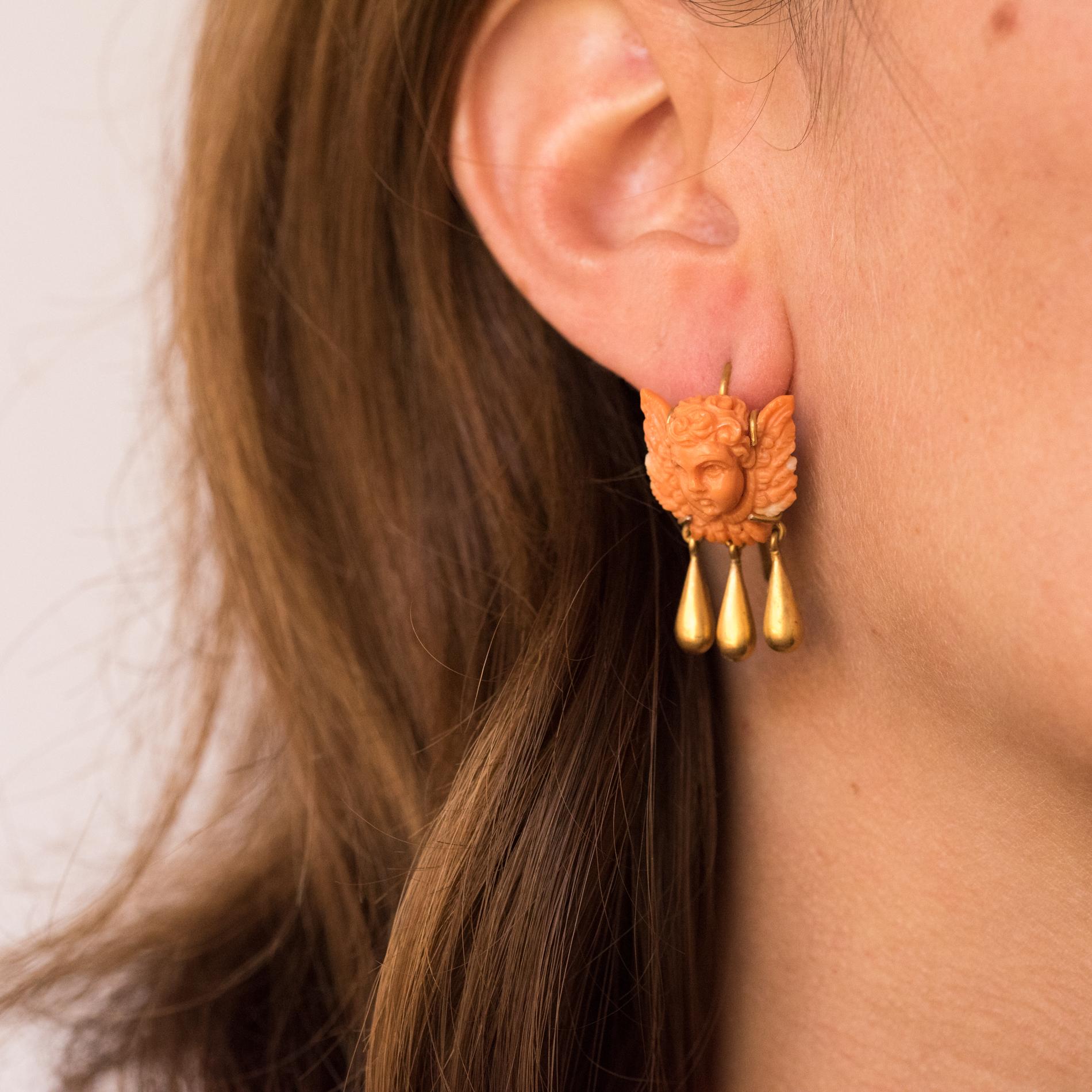 Earrings in 14 karats gold.
These charming earrings are made of a coral cameo representing a cherub, that holds in pendant 3 drops of gold. The clasp is a gooseneck.
Height: 30 mm, width: 16 mm, thickness: about 9 mm.
Total weight of the jewel: 8 g