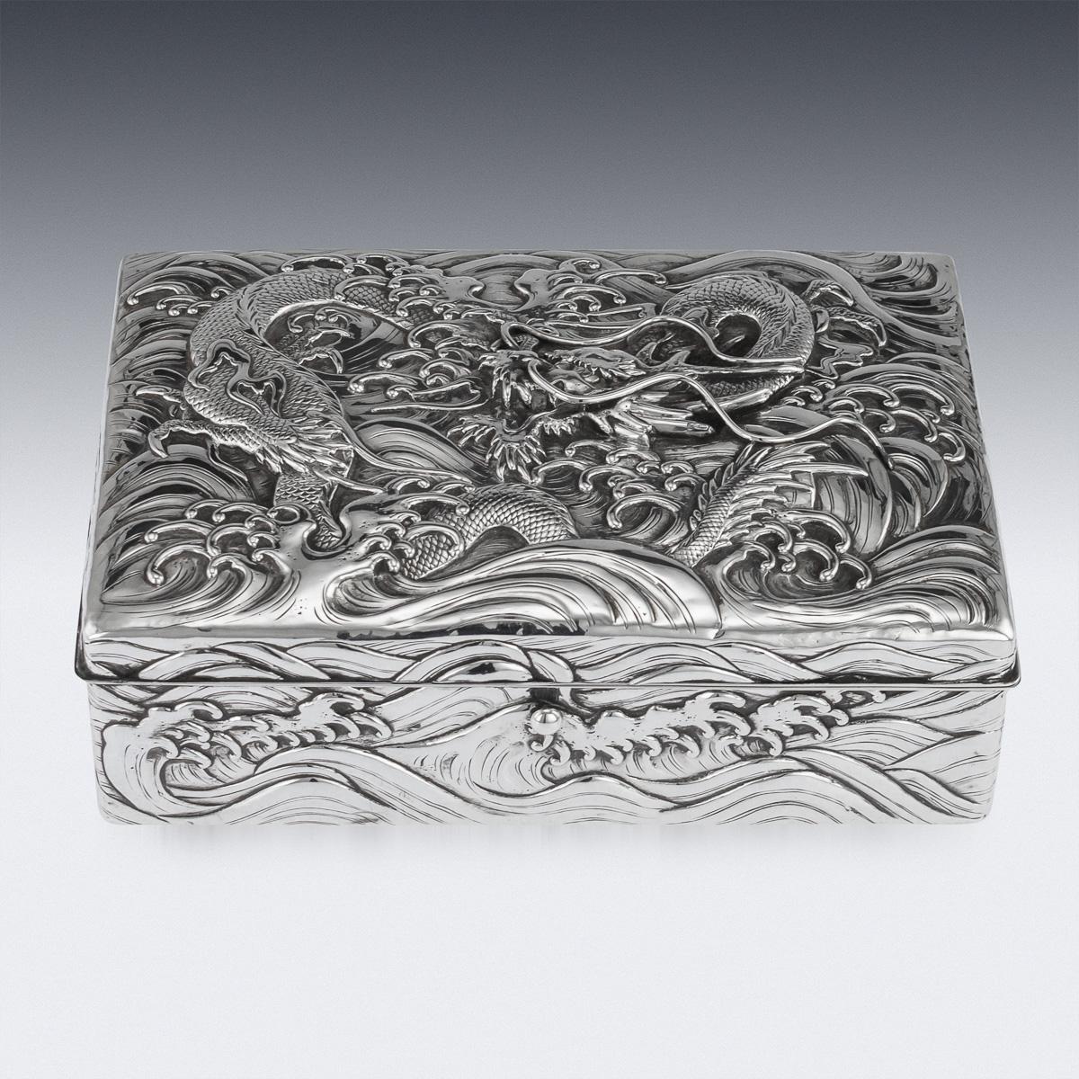 Antique early 20th century Japanese Meiji period solid silver cigar box, double skinned body, sides and lid are embossed in high-relief with water dragons and applied with flowing whiskers on hand hammered ground, dark wood lined base and interior.