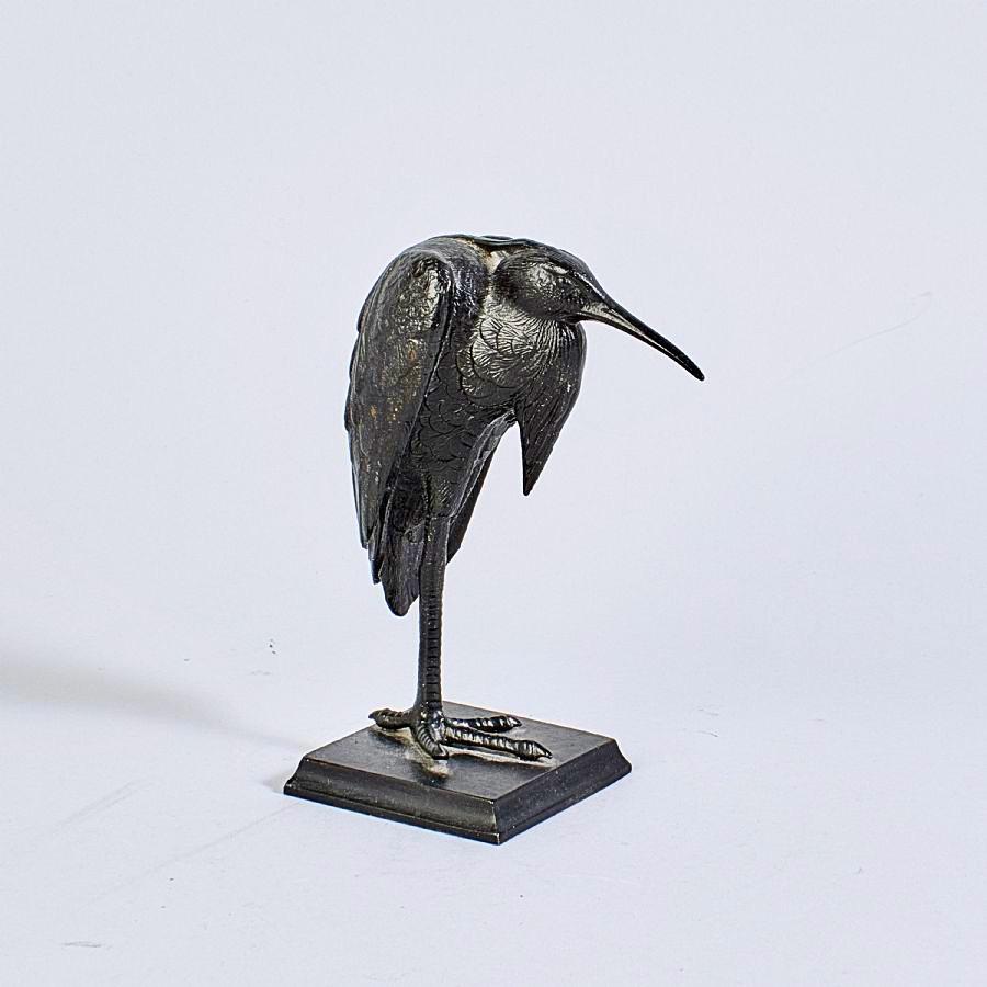 A highly decorative painted cast iron heron, crafted in the Japanese style during the first half of the 20th century. Standing gracefully on one leg with its neck tucked in, the heron embodies a pose commonly associated with tranquility and balance