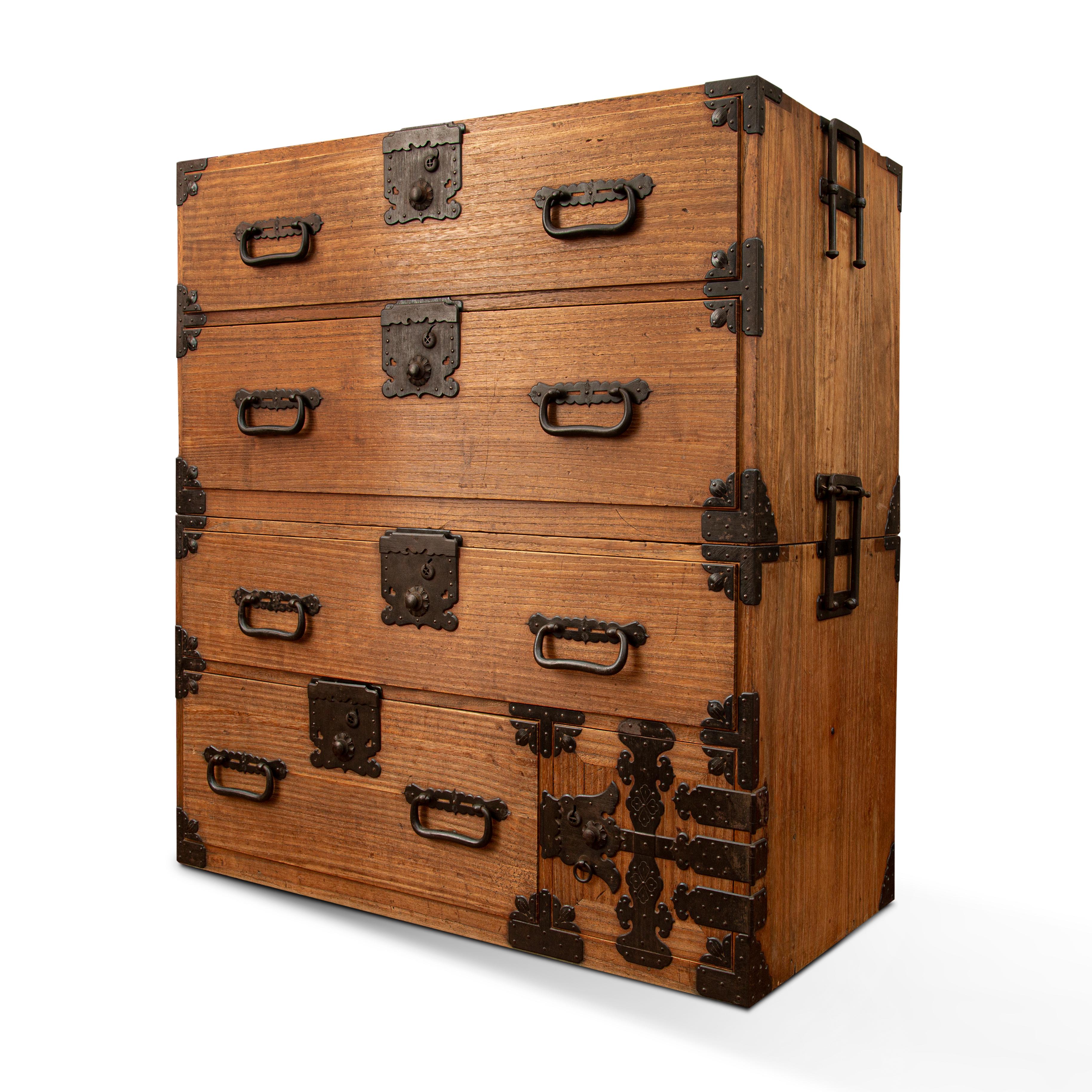 Crafted in Japan during the 20th century, this Pauownia wood (Kiri in Japanese ) tansu chest is a fine example of Japan's traditional mobile cabinetry. The long side handles flip up to permit a pole to be inserted so the chest can be carried by two