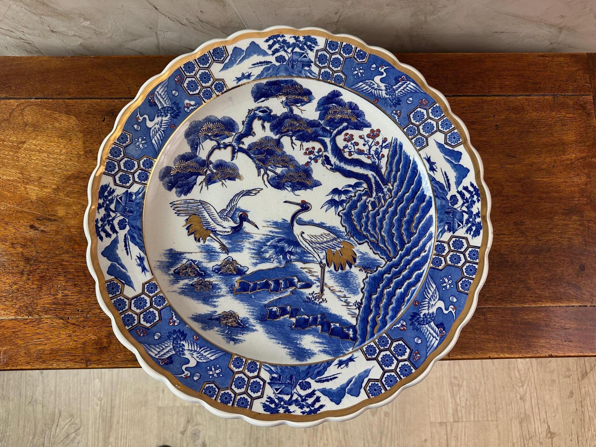 Très grand plat japonais en porcelaine bleue et blanche rehaussée d'or datant des années 50.
Décoration de grues dans un marais au pied d'un cerisier japonais en fleurs. Bordure avec motifs stylisés.
Parfait état. Pour les amateurs d'art et de