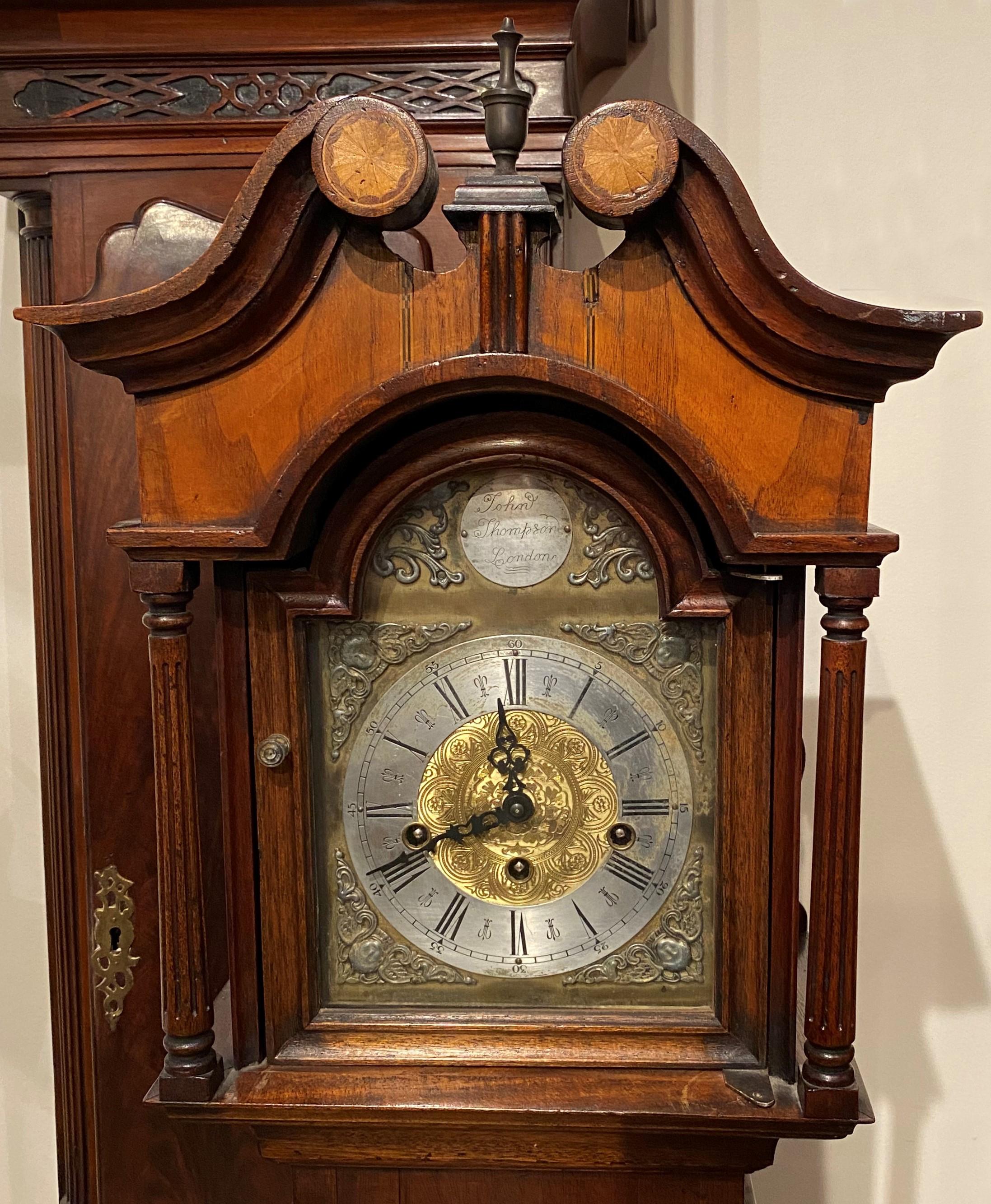 A fine example of a carved walnut & mahogany diminutive grandmother tall clock with a swan’s neck split pediment with inlaid full fan rosettes and a center urn finial surmounting a arch form glass door, opening to a brass arched Roman numeral dial