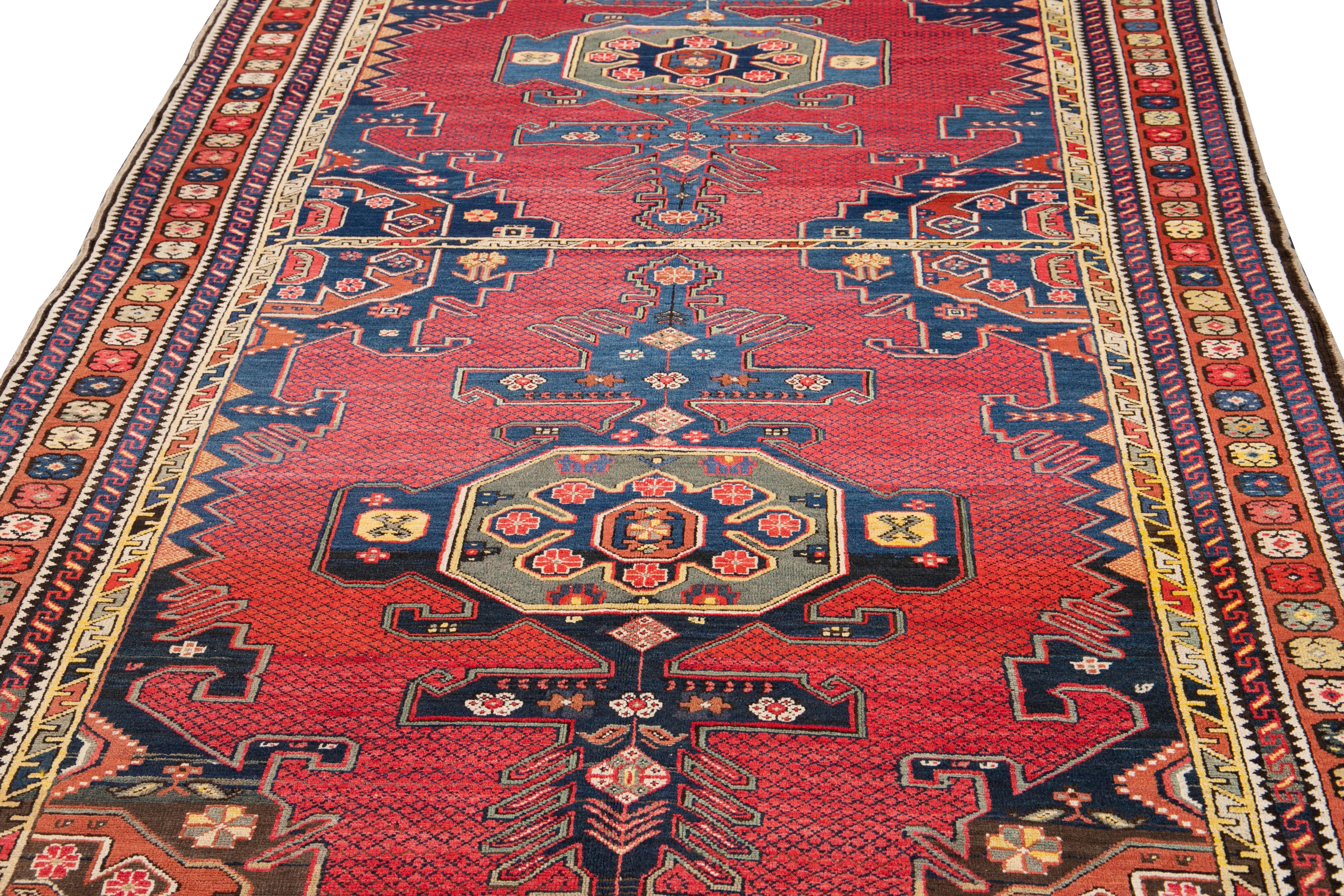 Schöner antiker, handgeknüpfter kasachischer Wollteppich mit einem roten Feld. Dieser Teppich hat einen rostfarbenen Rahmen und gelbe, blaue und graue Akzente mit einem geometrischen Tribal-Muster, das über den ganzen Teppich verteilt ist.

Dieser