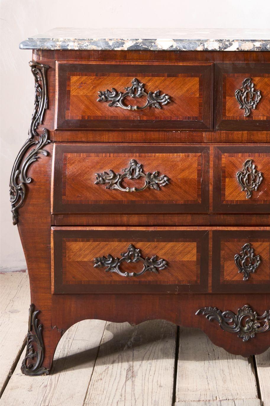 This is a very elegant 20th century chest of drawers. French in origin and made from kingwood with rosewood inlay. The heavy bronze handles and decoration are of high quality and suit the bold design of the piece perfectly. The dark colour of the