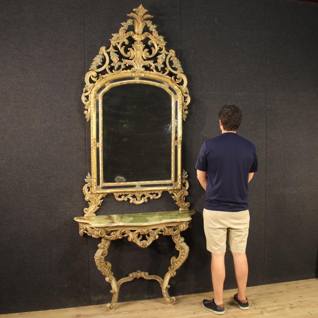 Console with mirror, Italy, mid-20th century. Furniture consisting of two elements, carved, lacquered and gilded wooden console, supported by two moved legs, to be fixed to the wall. Large and impact mirror, also in lacquered and gilded wood, of