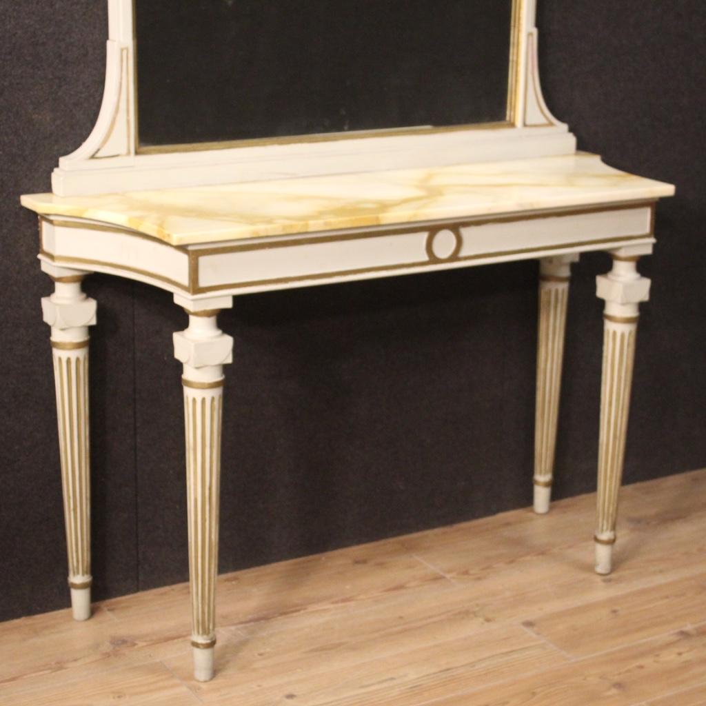 Italian console with mirror from the mid-20th century. Louis XVI style furniture in lacquered and gilded wood of beautiful line and pleasant decor. Console supported by four solid fluted legs with original marble top. Base mirror composed of three