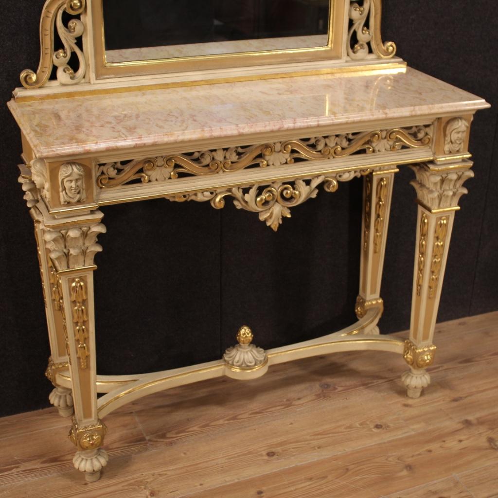 Console with Italian mirror from the 20th century. Louis XVI style carved, lacquered and gilded wood furniture of excellent quality and great impact. Console adorned with masks placed on the front and on the sides above the front palmette columns
