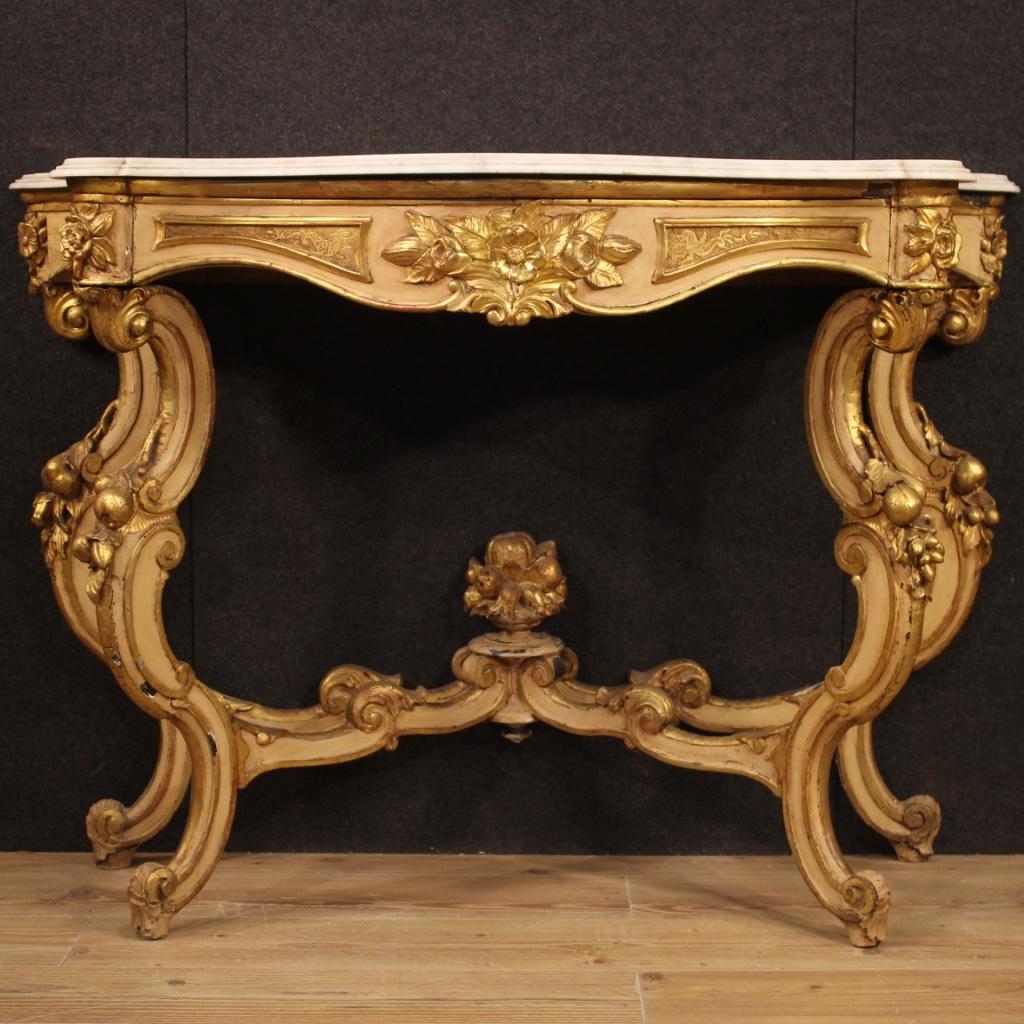 Italian console from the mid-20th century. Furniture in carved, lacquered and gilded wood in Louis Philippe style. Wall console supported by four moved legs with central connection, richly adorned with decorations with flowers and fruit (see photo).