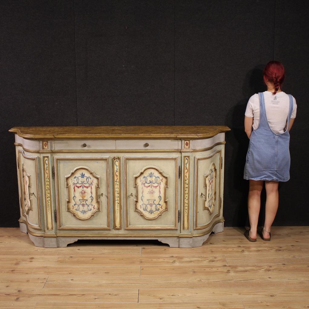 Aparador veneciano de la segunda mitad del siglo XX. Un gran mueble de gran calidad fabricado en madera tallada, lacada y pintada con exquisitas decoraciones neoclásicas. Este aparador de cuatro puertas presenta una tapa de madera con acabado lacado