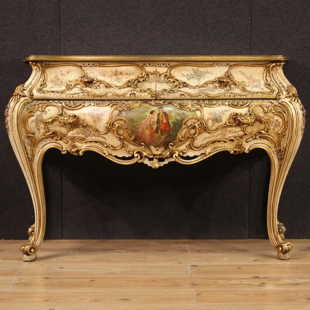 Venetian chest of drawers from the mid-20th century. Moved and rounded furniture richly sculpted with relief decorations on the front and sides (see photo), lacquered, gilded and painted with flowers and romantic scene. Commode equipped with two