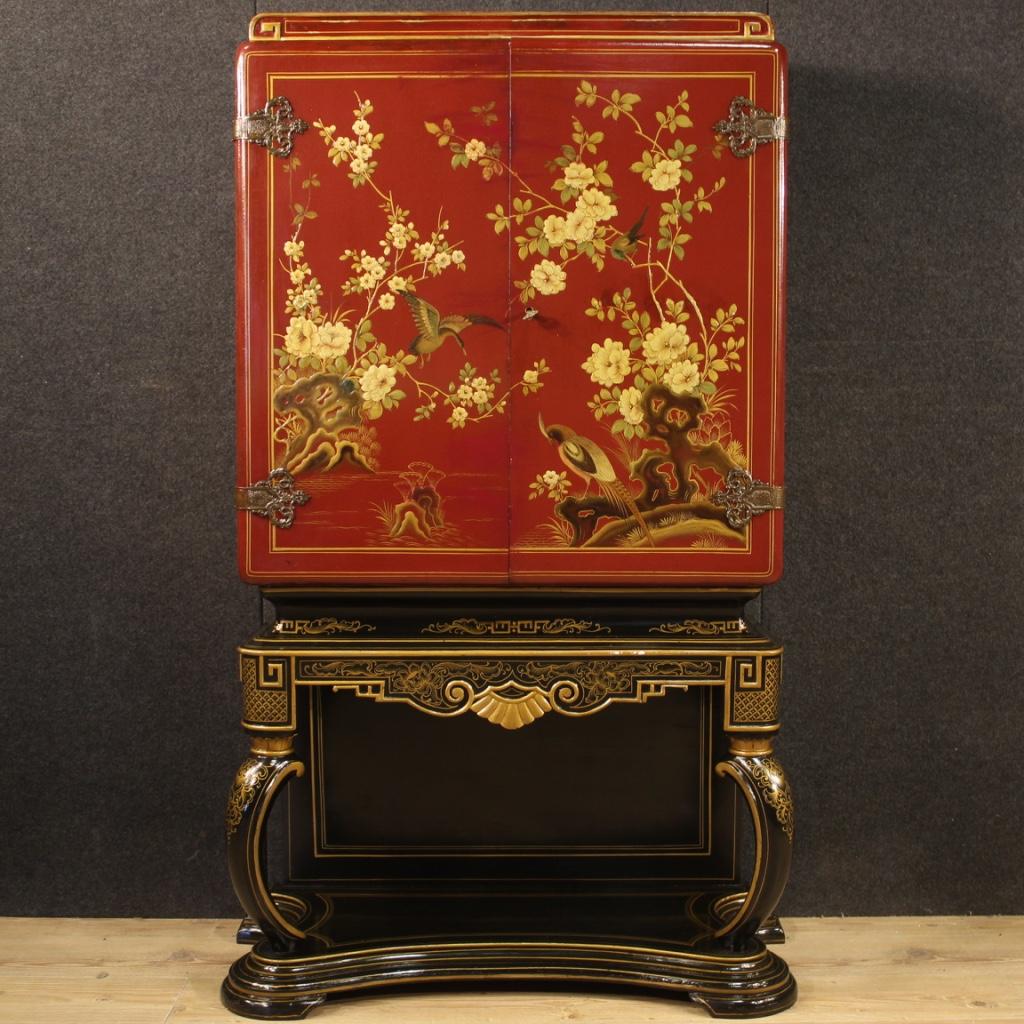 Italian bar cabinet from the 1960s-1970s. Cabinet in carved and lacquered chinoiserie of fabulous decor. Double body furniture, equipped with two doors and working key of good capacity and service. Lower body in dark lacquer with golden decorations