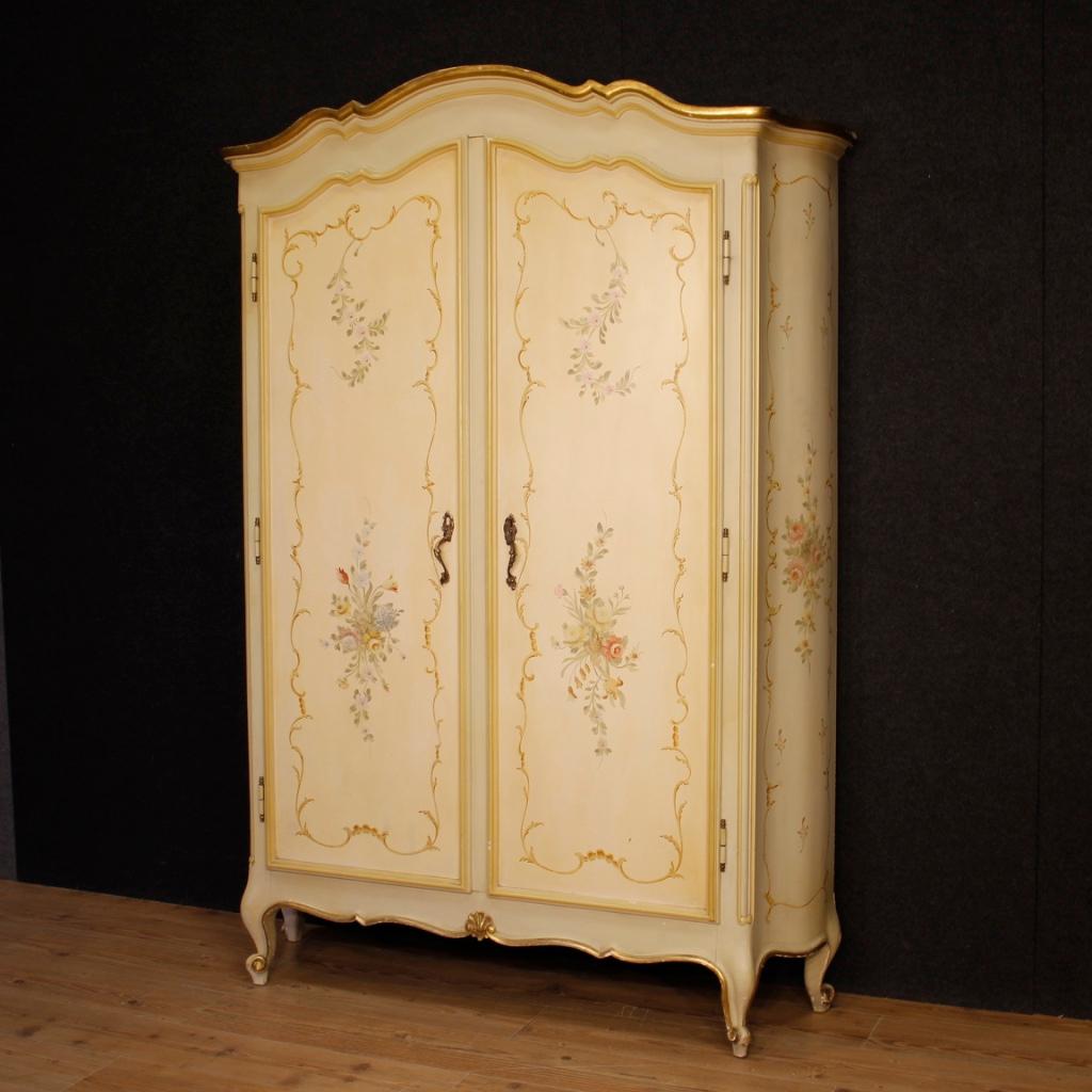 20th century Italian wardrobe. Furniture in carved, lacquered, gilded and hand painted wood with very pleasant floral decorations. Entrance armoire with two doors, equipped with an internal coat hanger and a good service hatbox. Particularly