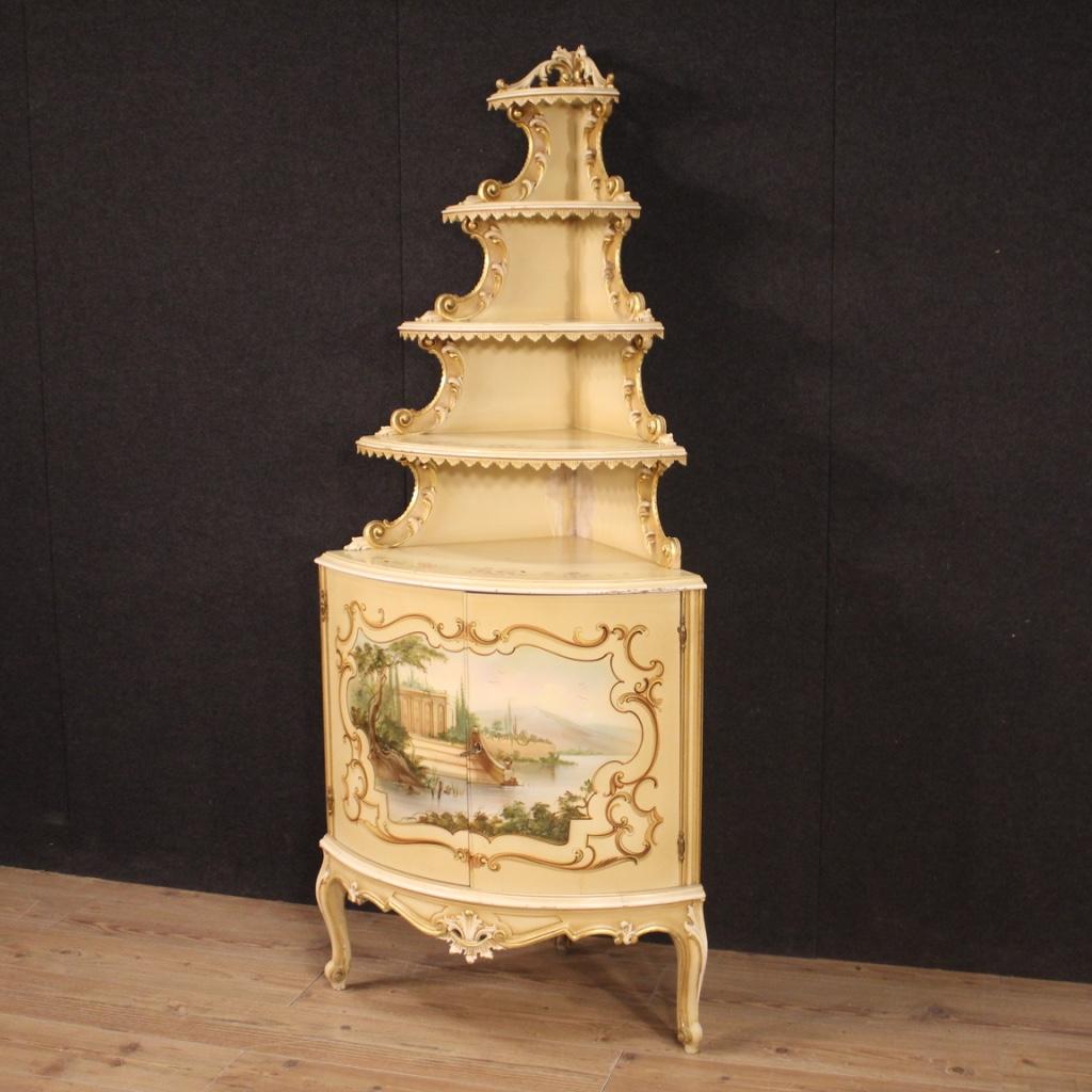 Italian corner cupboard from 20th century. Furniture in carved, lacquered, gilded and painted wood with landscape on the two front doors. Double body corner cupboard with upper open element fitted with several shelves. Lower body with two doors of